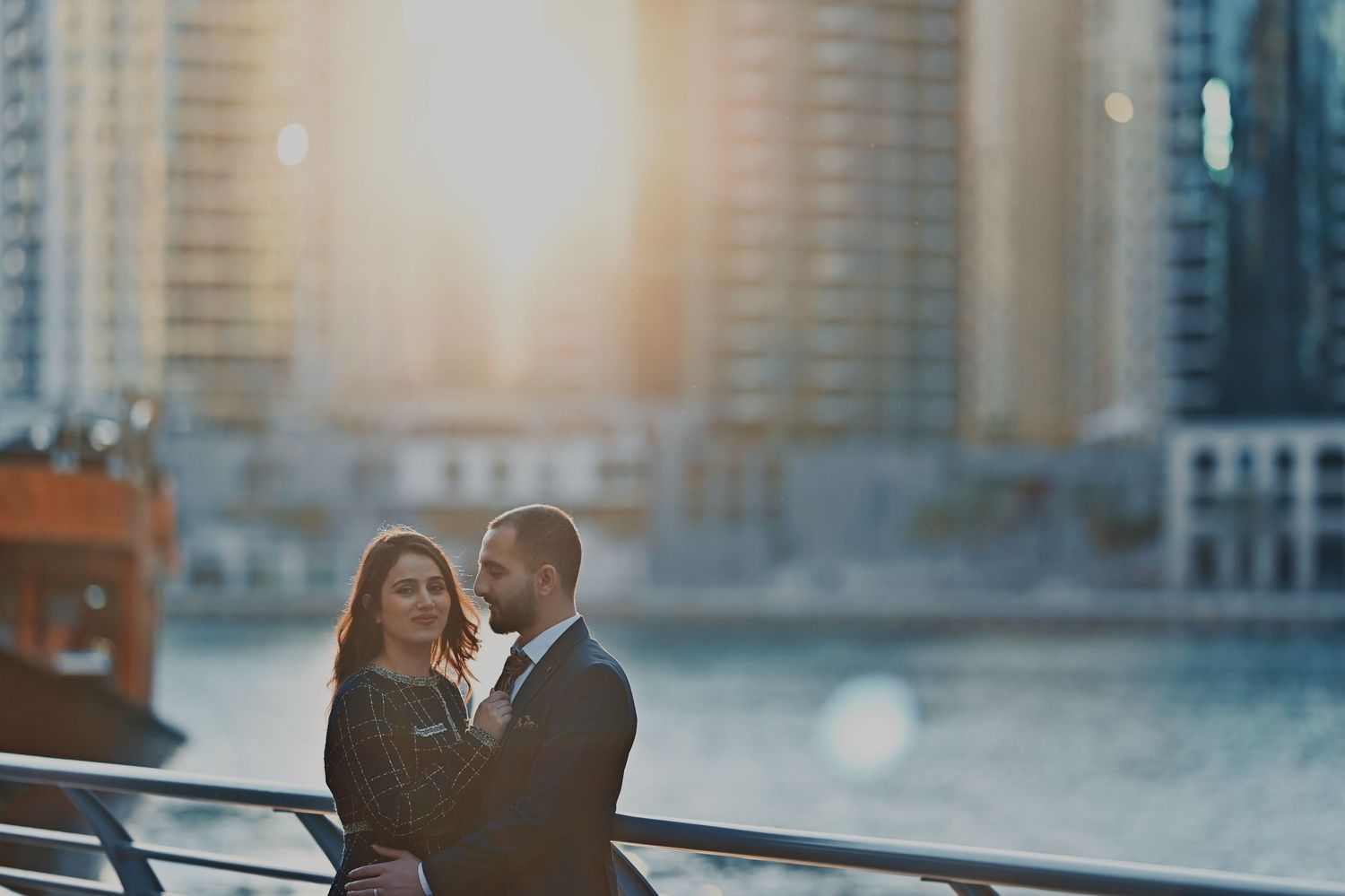 Couple sharing a tender moment with urban architecture in the background at sunset.