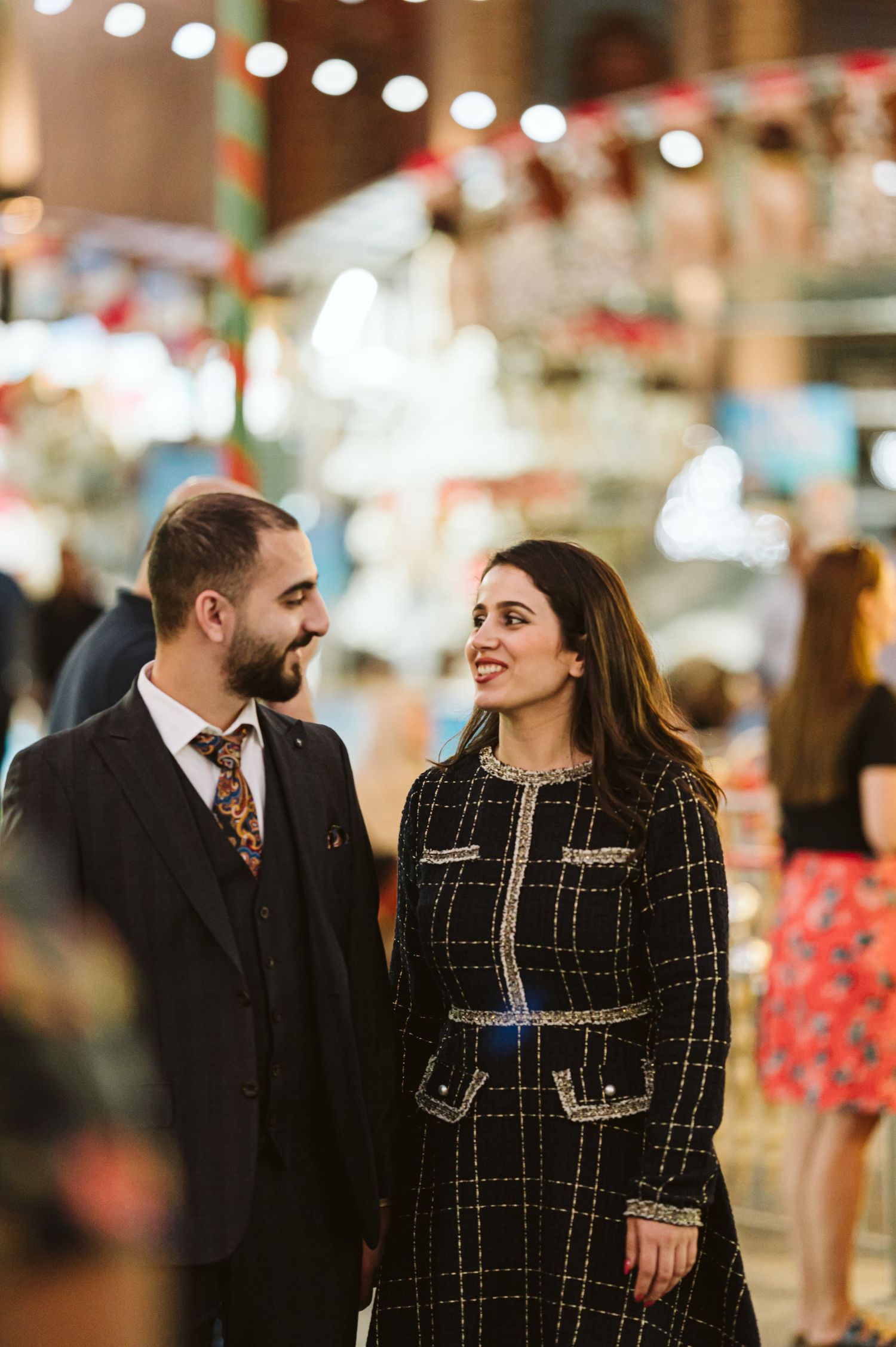 A couple shares an intimate moment under twinkling lights in an indoor venue.