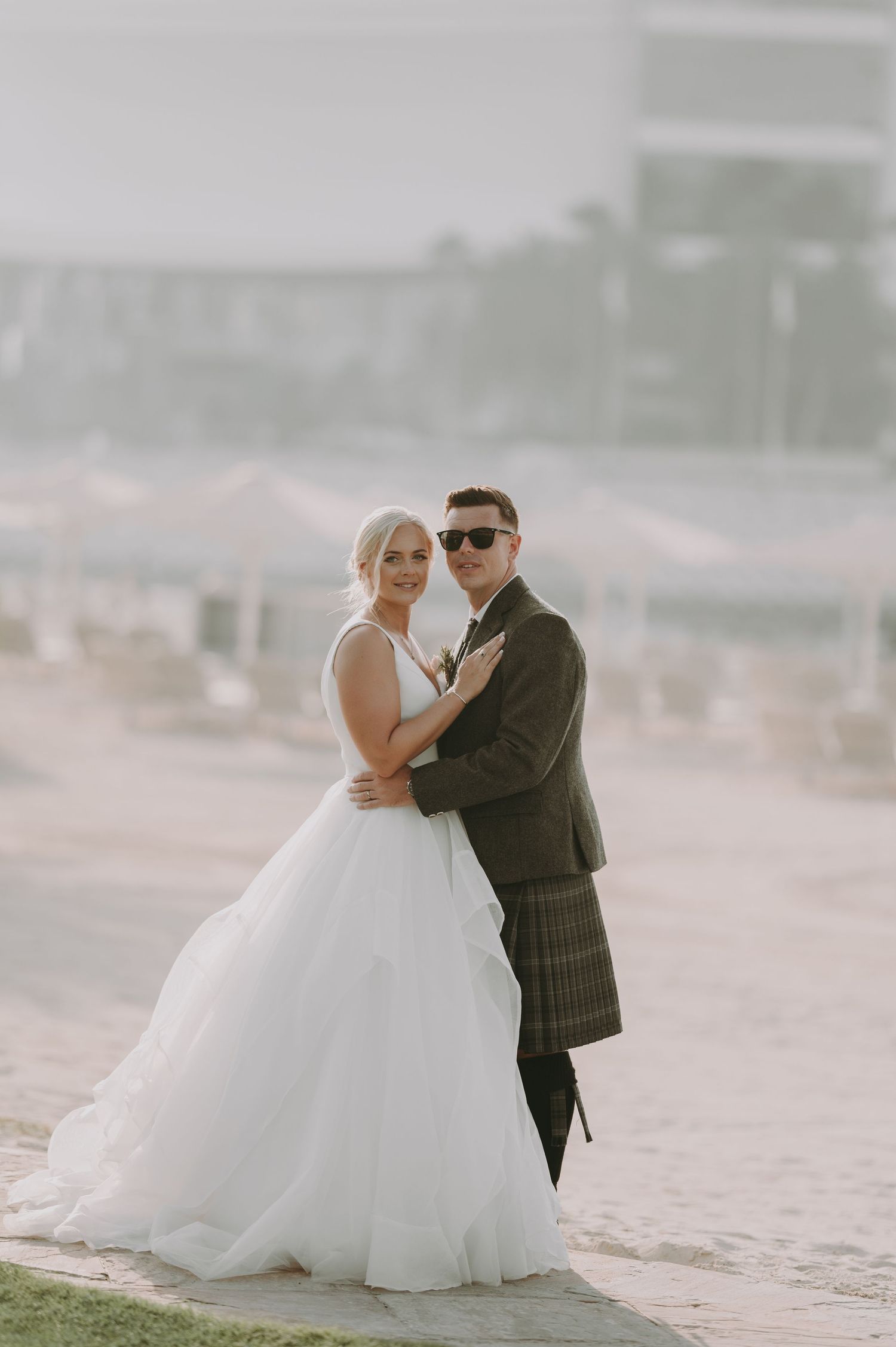 A couple embraces during their beach wedding photoshoot in ethereal lighting.