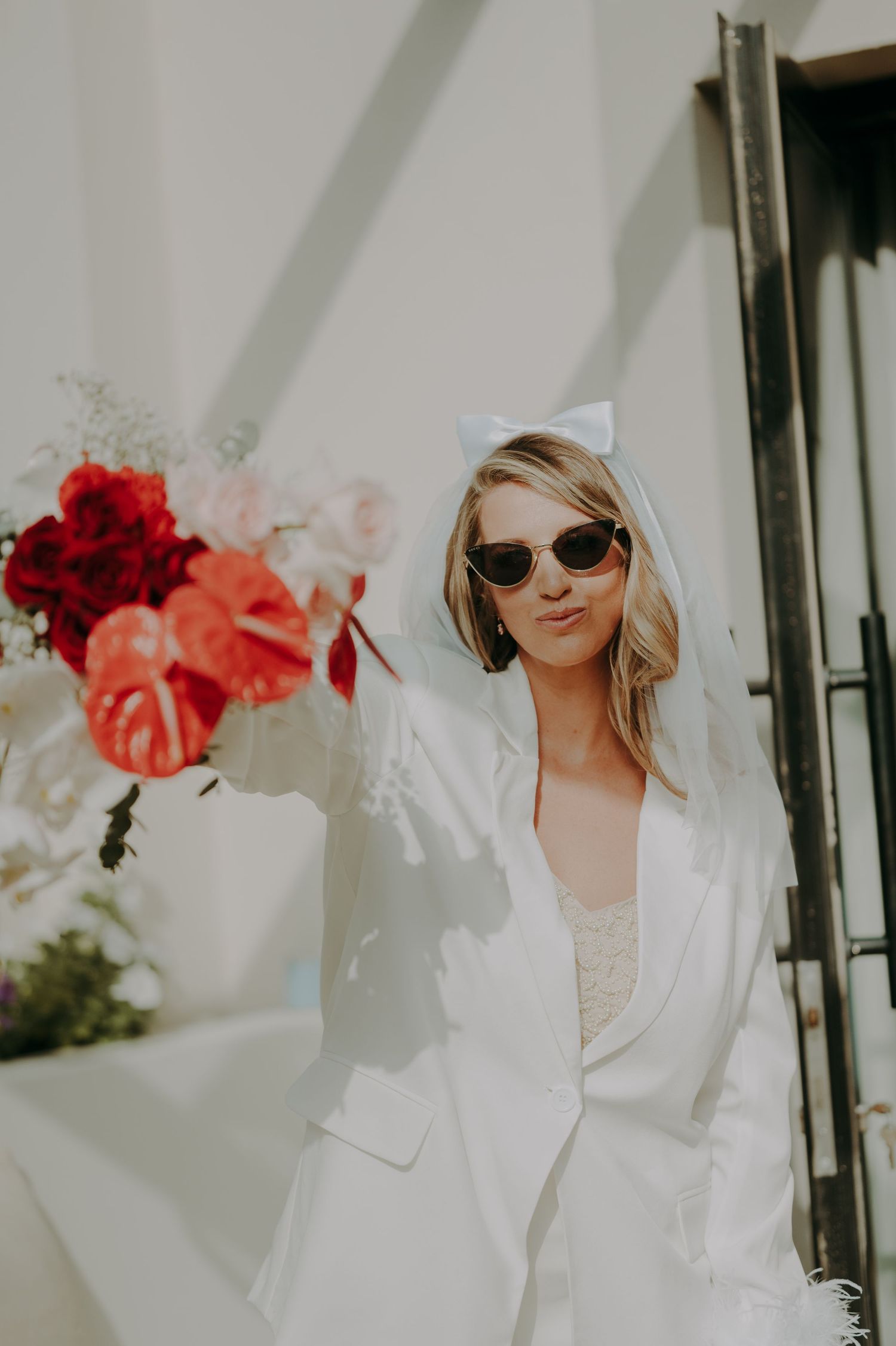 Stylish bridal photos with sunglasses and red flowers against a white background.
