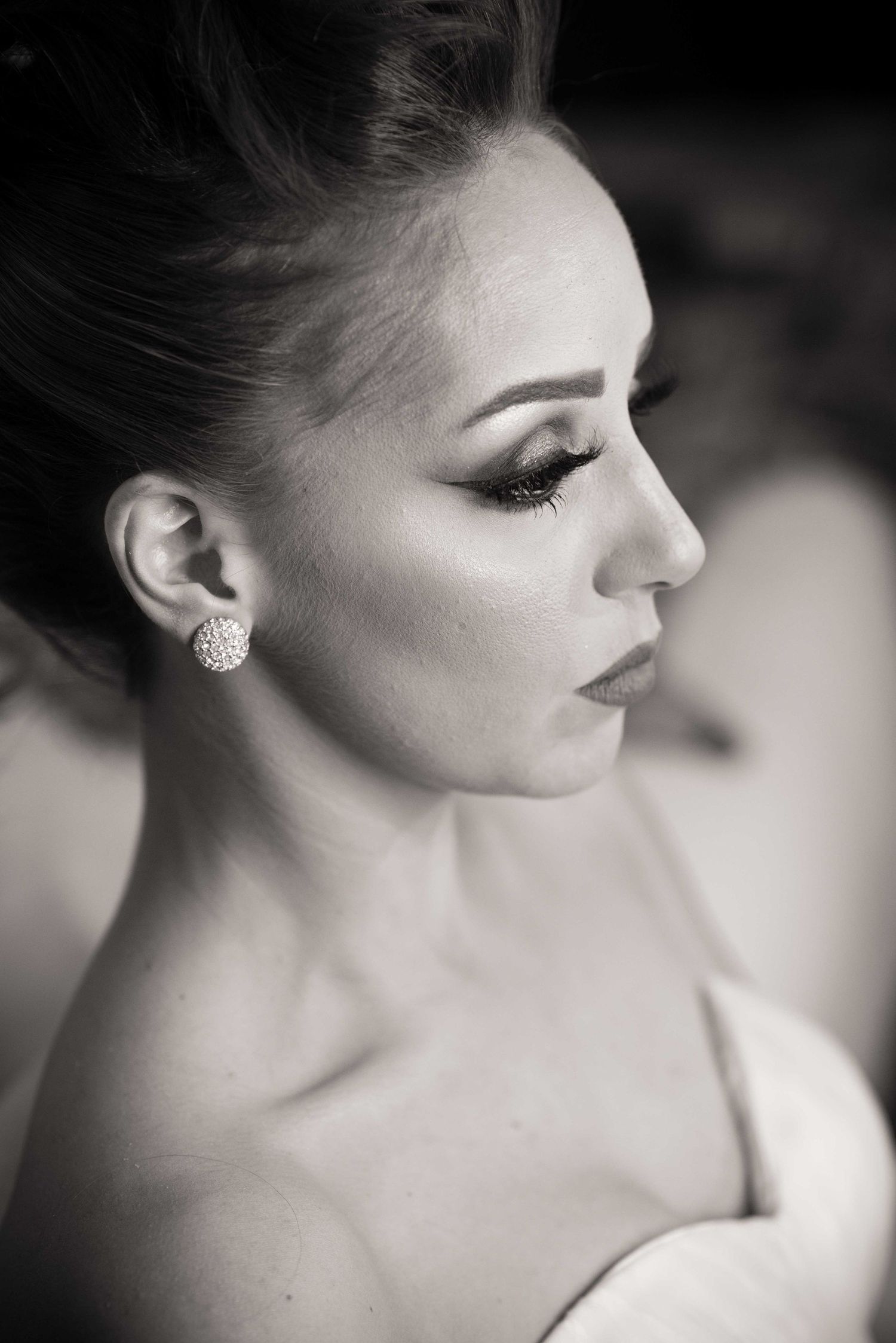 Close-up black and white portrait showing refined makeup and crystal earring.