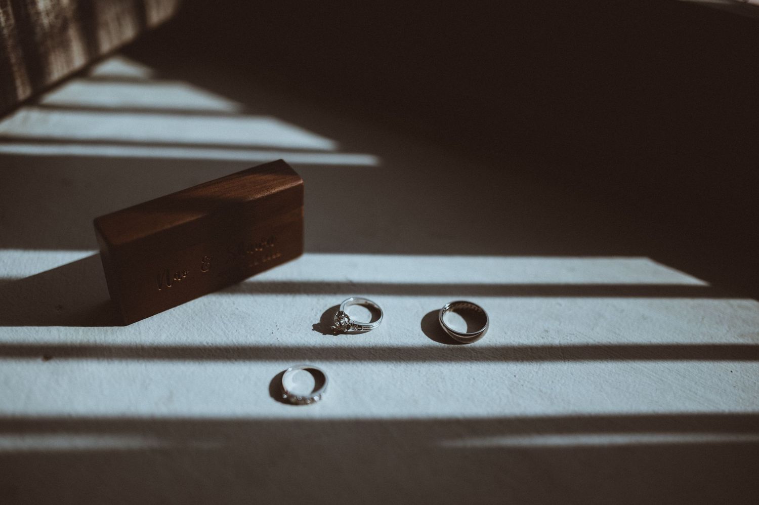 Wedding rings casting dramatic shadows in black and white minimalist photography.