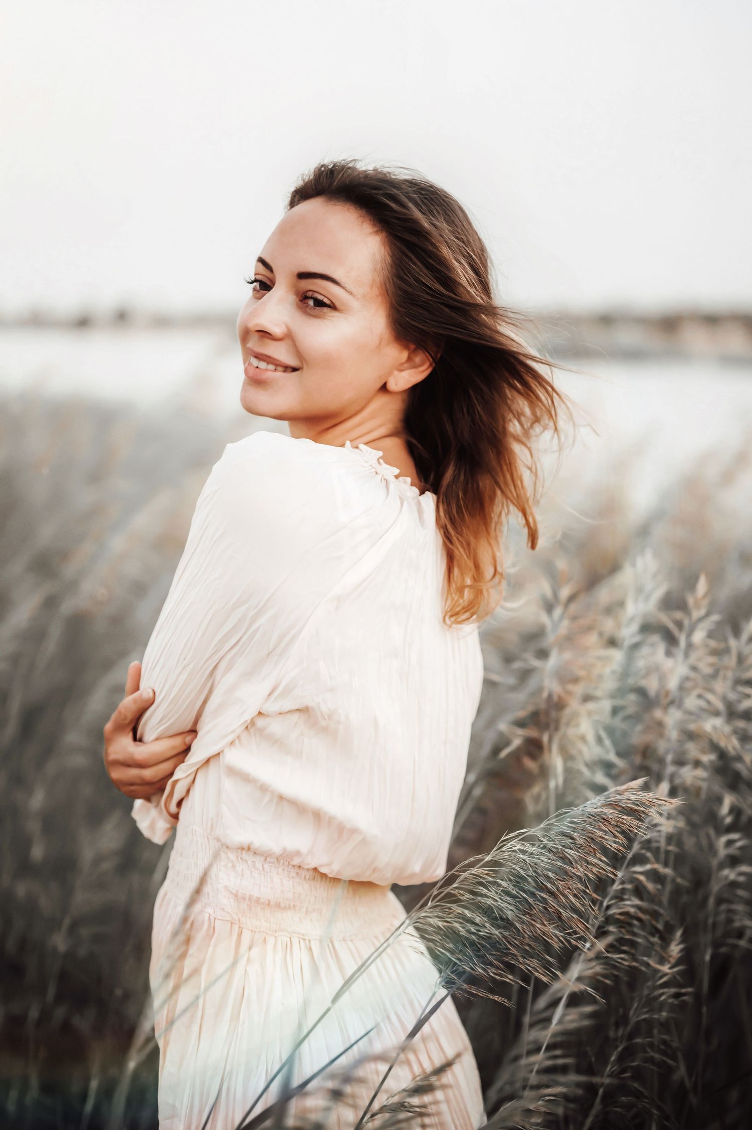 Portrait among tall grass with flowing white dress and natural backlighting.
