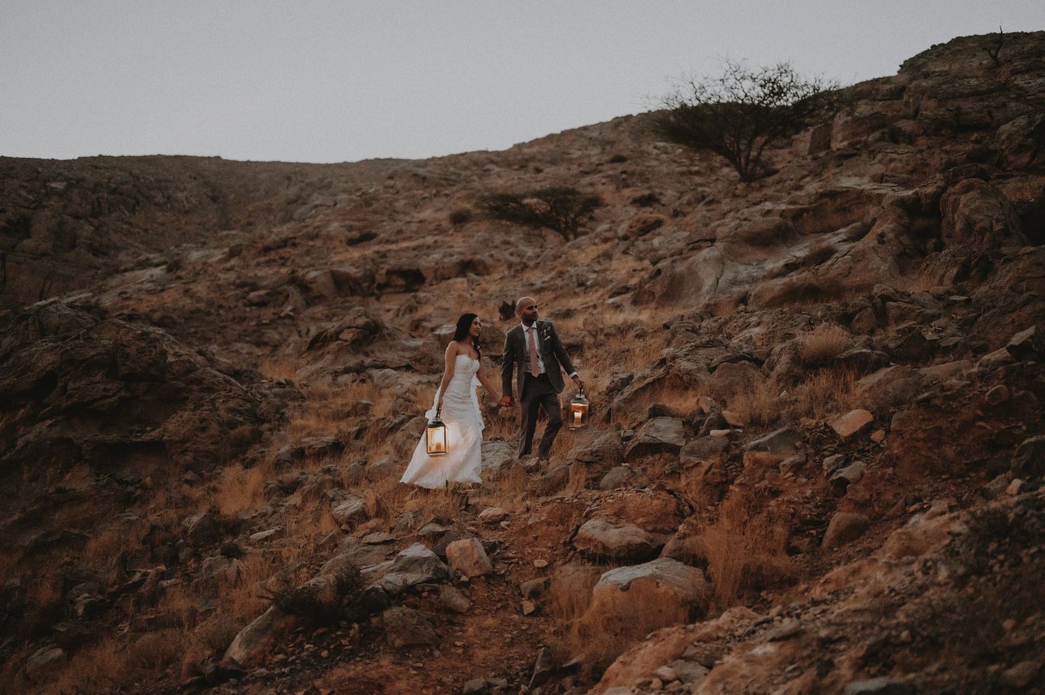 Desert wedding photography featuring couple on rocky terrain with dramatic mountain backdrop.