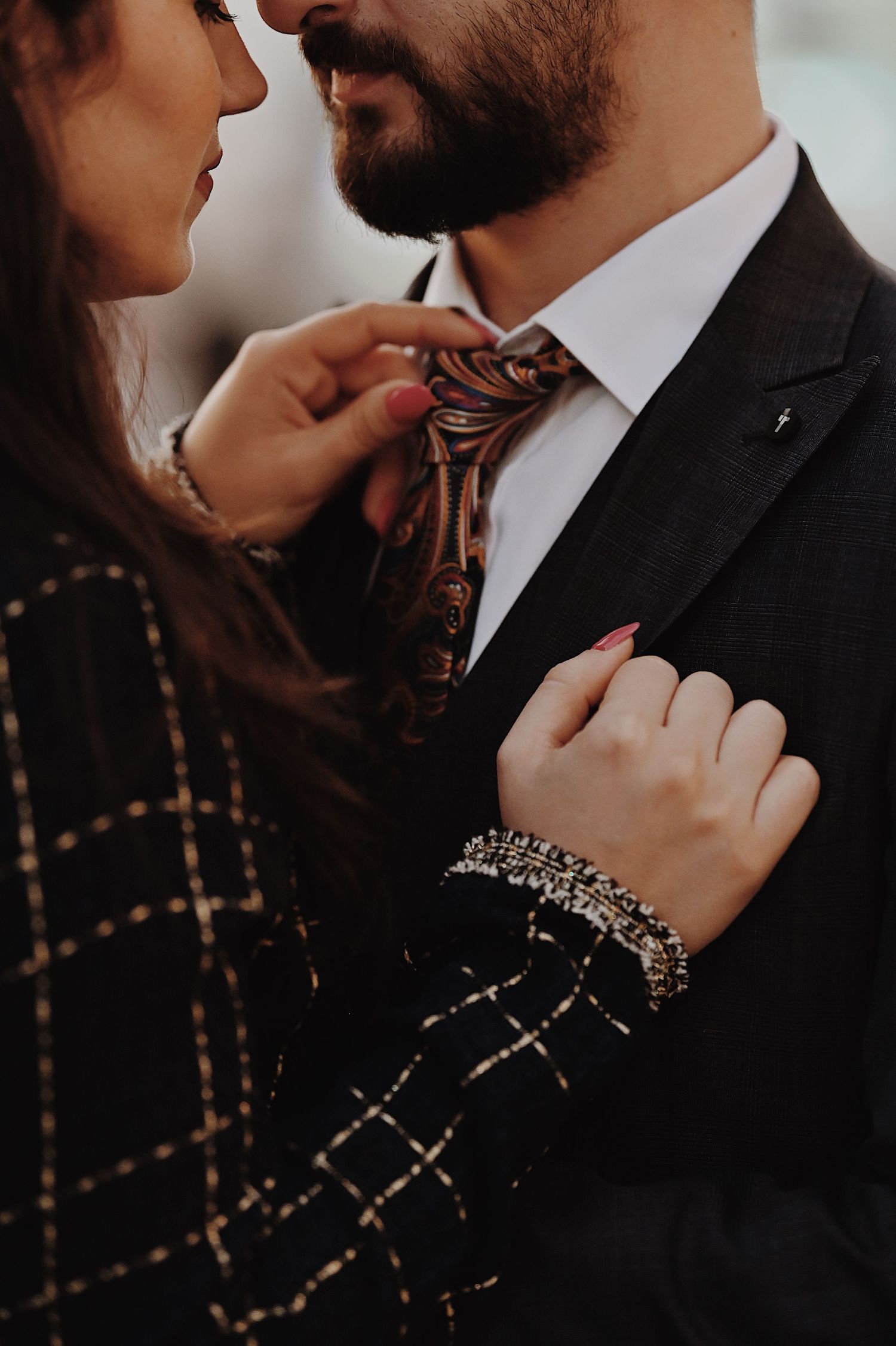 Close-up shot of couple in formal wear with focus on elegant jewelry and details.