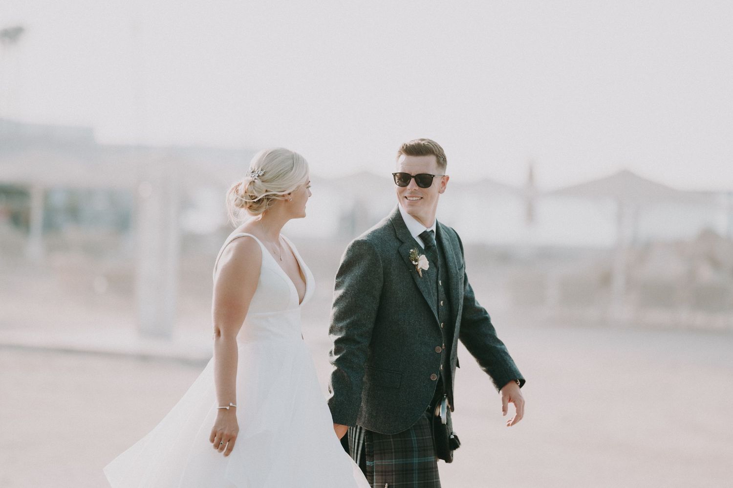 Wedding couple walking together in bright desert landscape.
