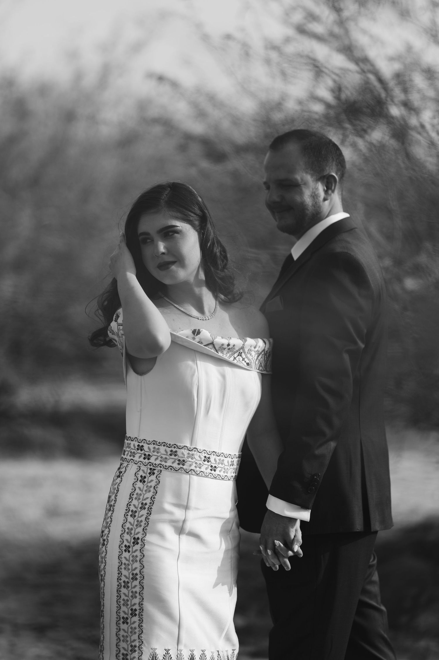 Black and white wedding photo captures a couple's intimate moment in natural outdoor lighting.