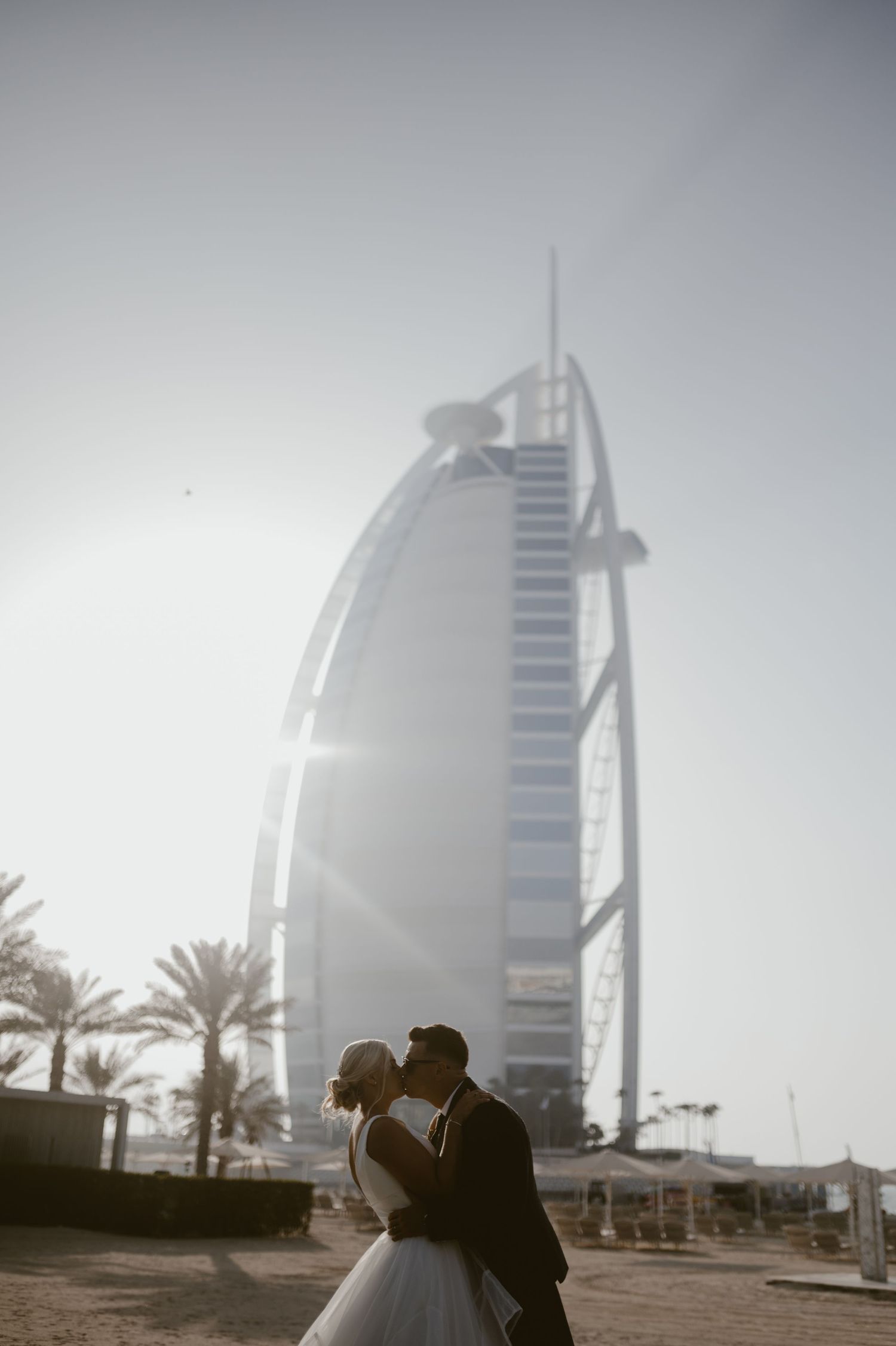 Wedding photo with iconic Burj Al Arab hotel in Dubai visible in the misty background.
