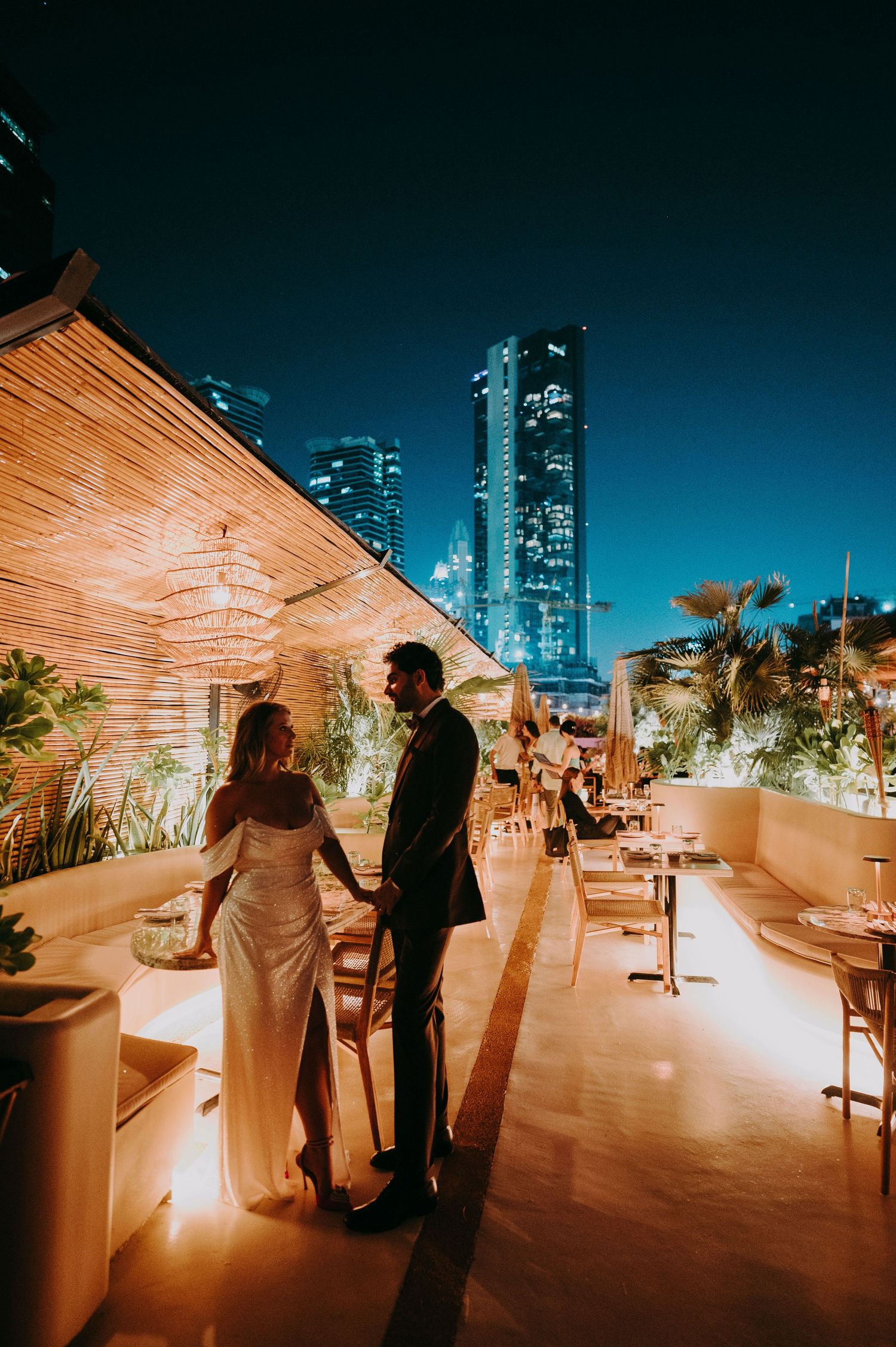Romantic rooftop wedding scene with city skyline and warm lighting.