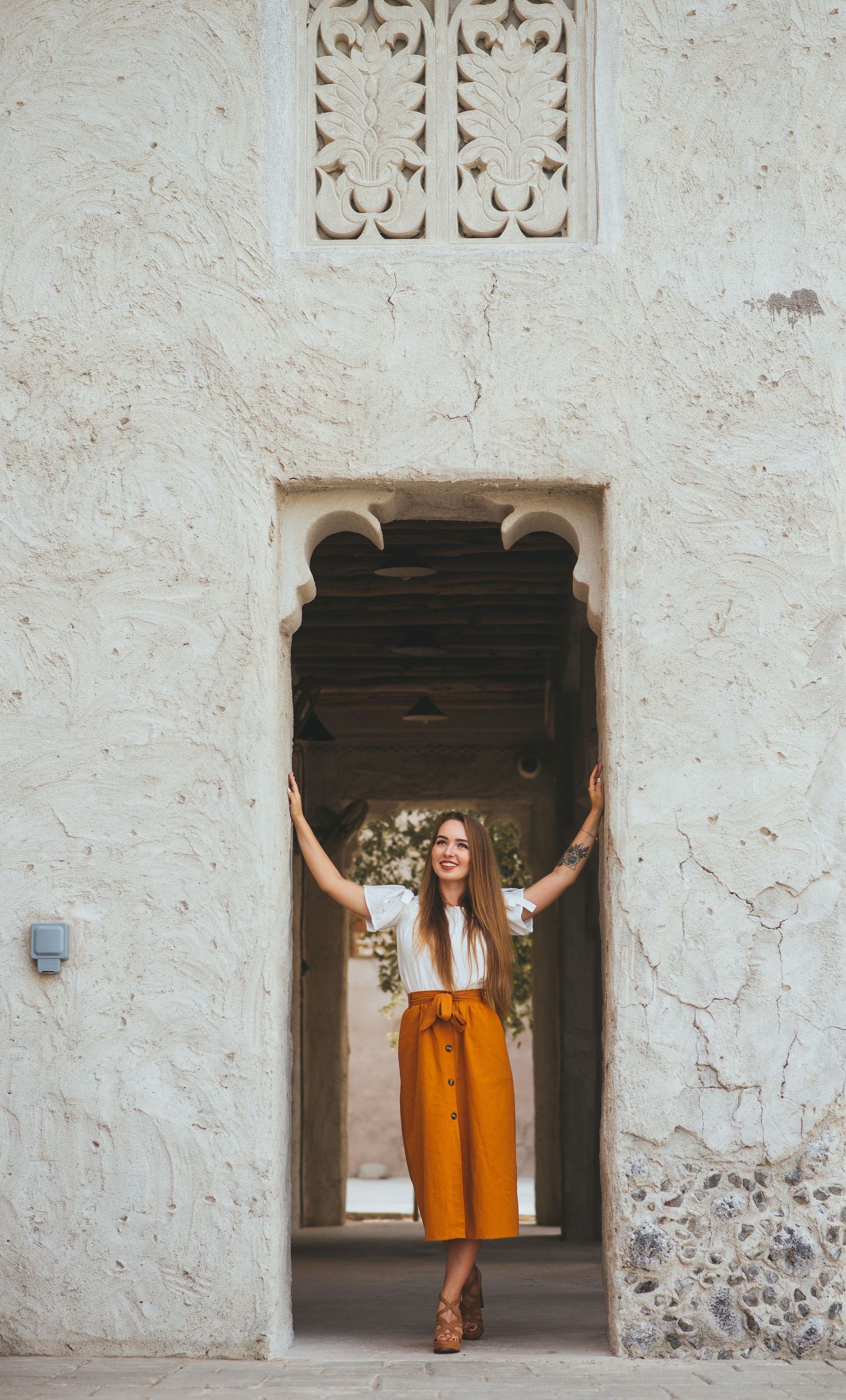 White stone archway framing person in bright orange outfit.