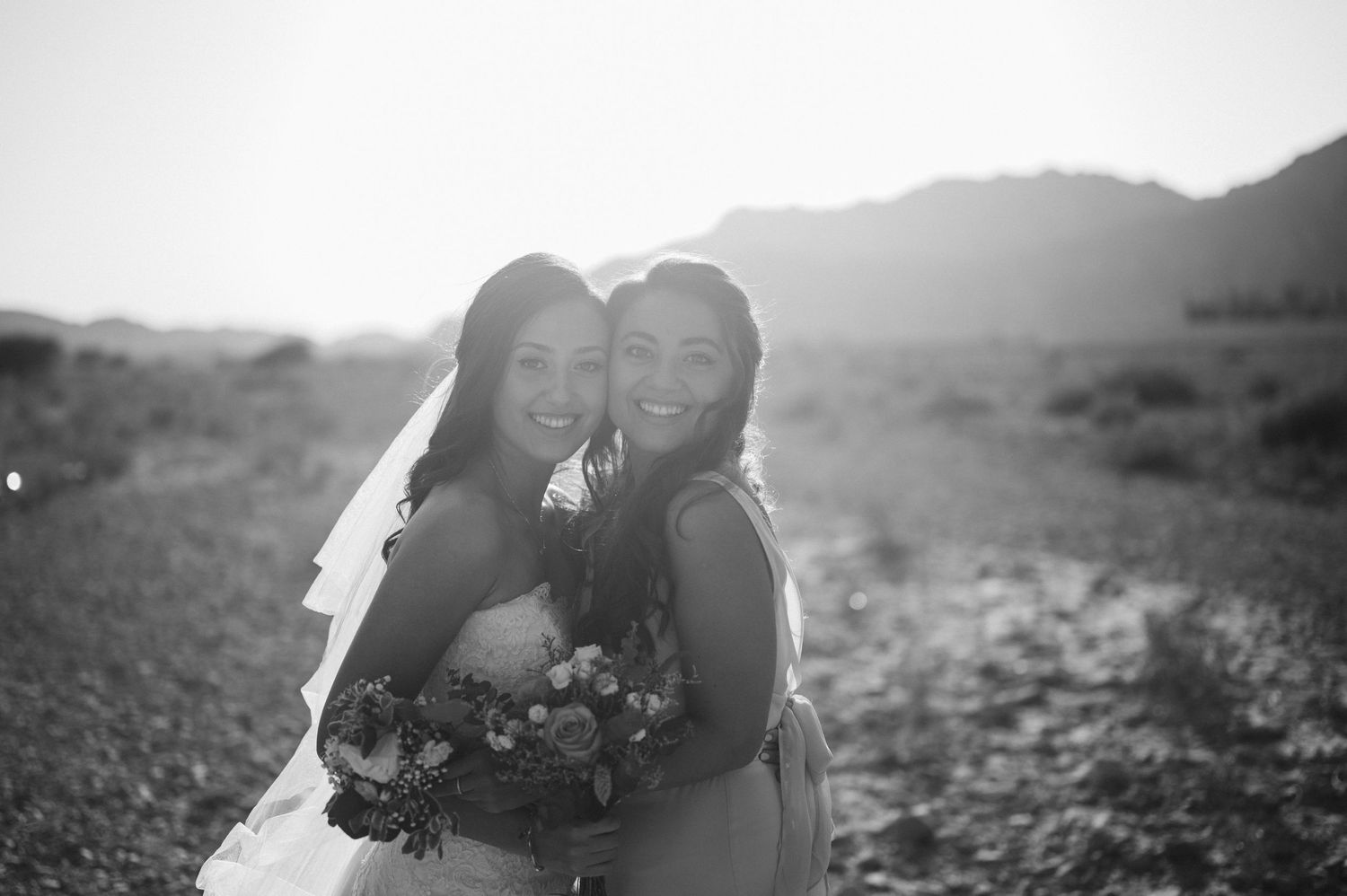 Intimate black and white wedding portrait captured in desert setting with natural lighting.