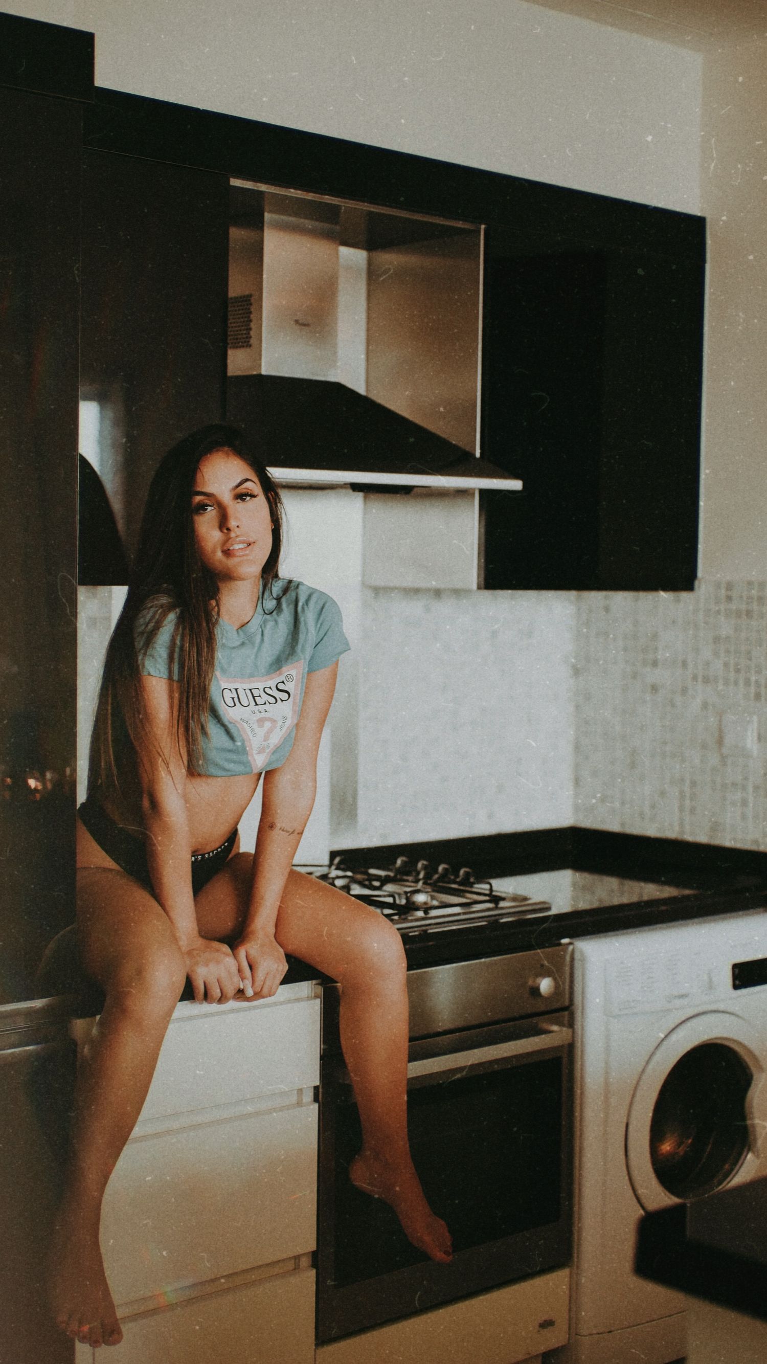 Candid lifestyle photo of a woman relaxing in a modern kitchen setting.