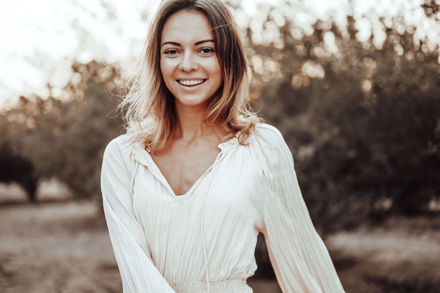 Close-up portrait with warm sepia tones and natural outdoor lighting.