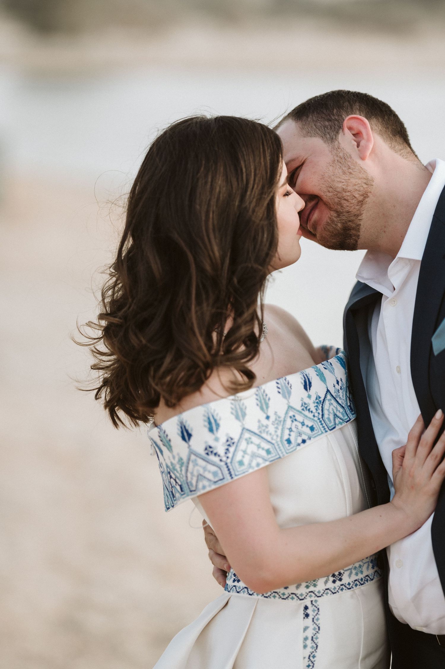 Close-up wedding photos showing tender moments and details of a white dress with blue accents.
