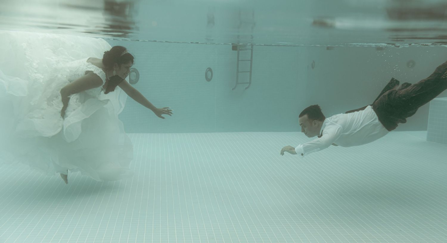 Multiple shots of swimmers moving underwater in a swimming pool with soft lighting.