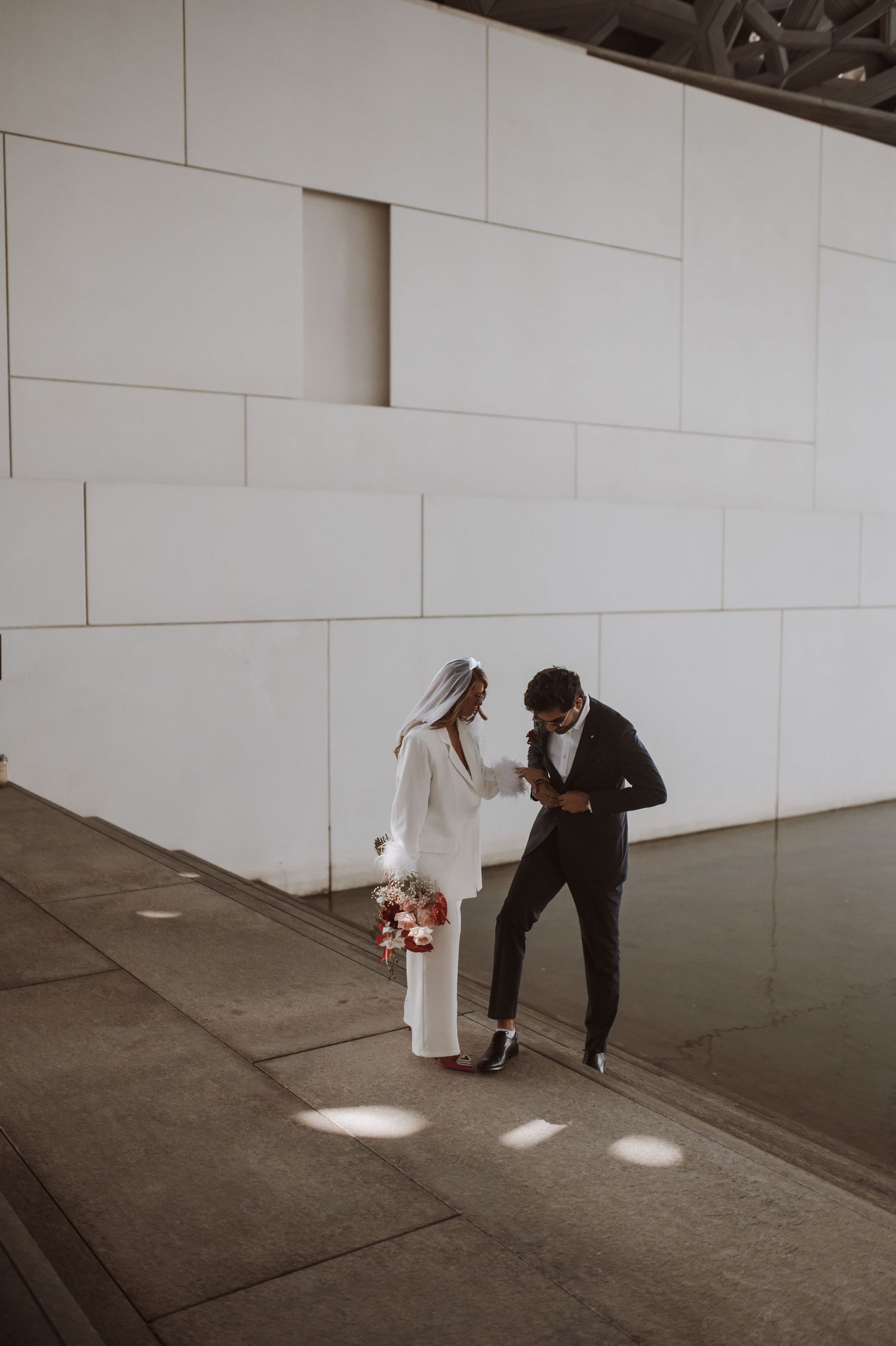 A couple sharing an intimate moment against a white geometric wall.
