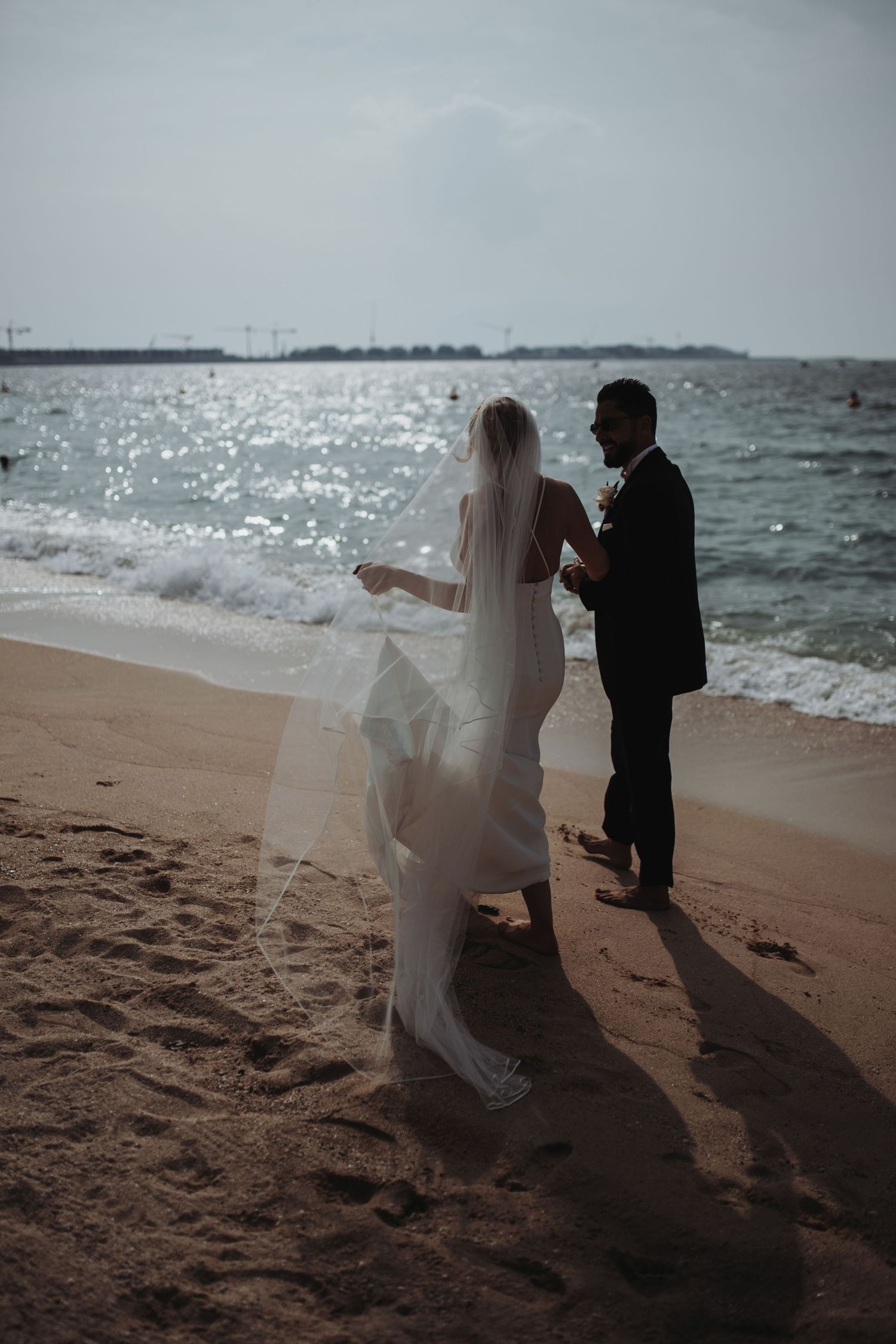 Romantic beach wedding photoshoot with flowing white veil catching the ocean breeze.