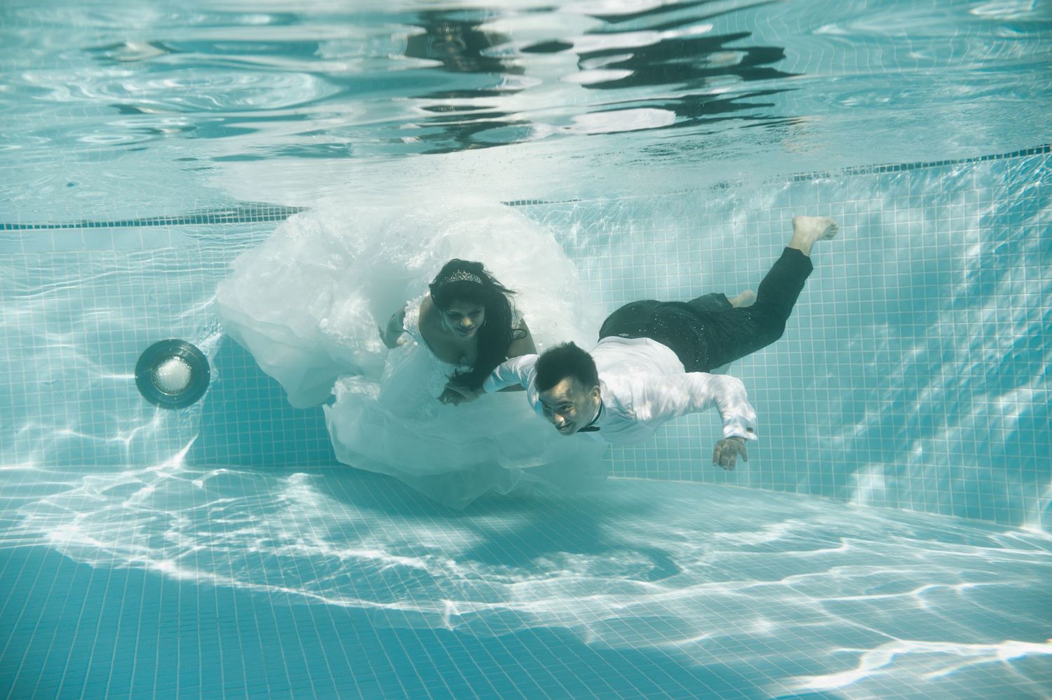 Underwater sequence showing swimmers gliding gracefully through turquoise pool water.