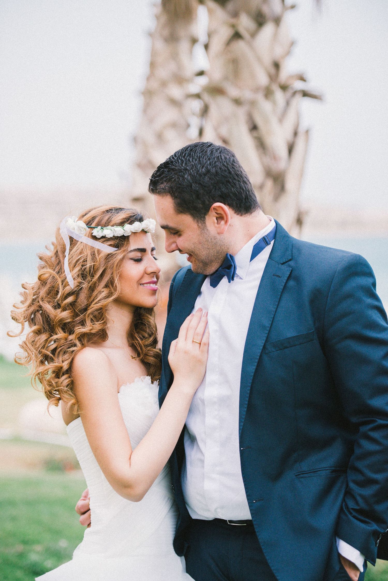 Romantic wedding portraits with couple in formal attire under palm trees.