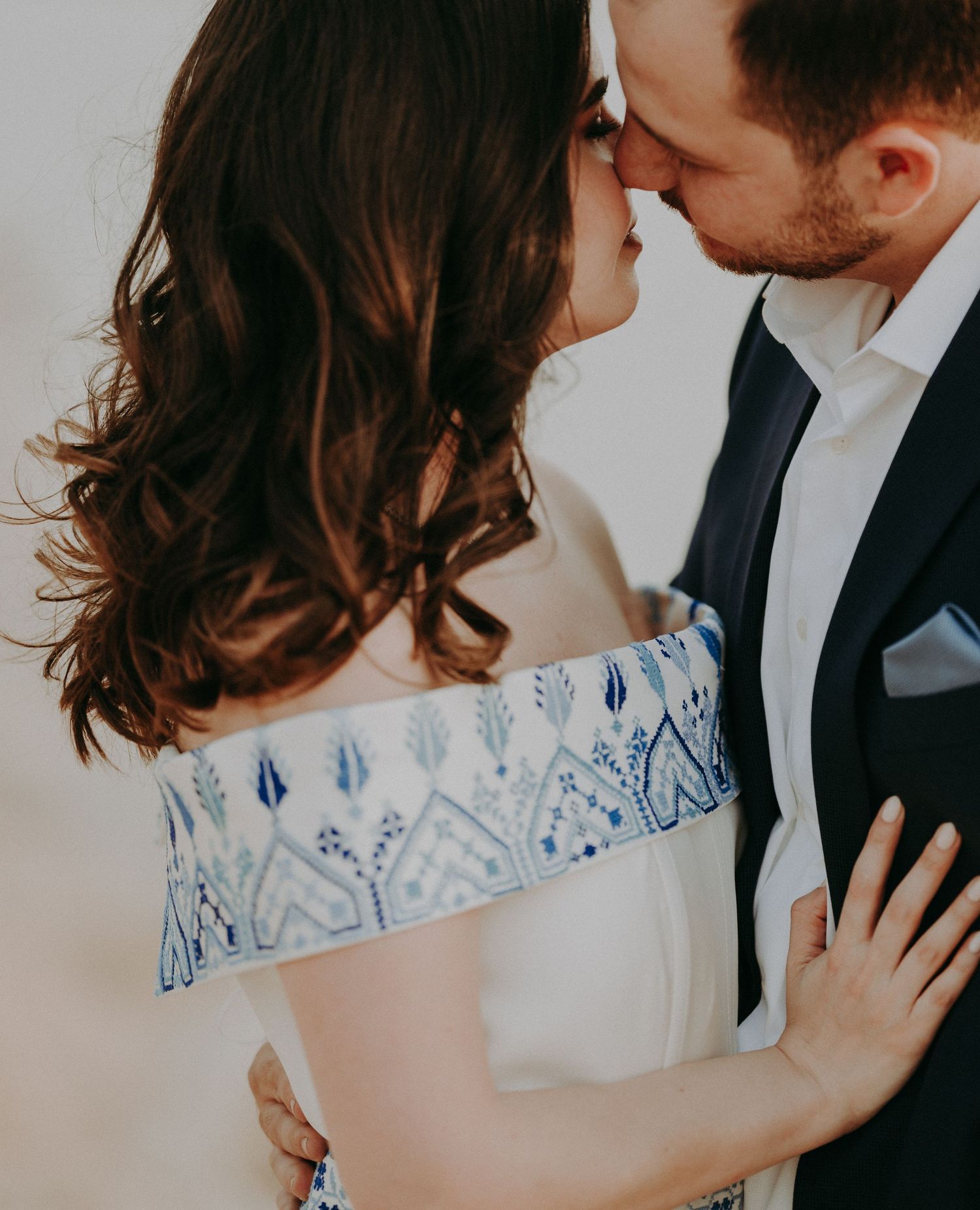 Series of tender wedding portraits showcasing an ornate white dress with blue embellishments.