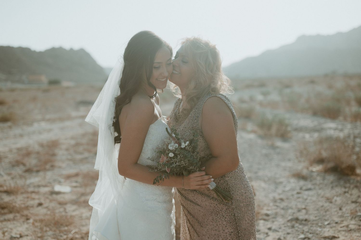Romantic desert wedding portraits with soft lighting and natural mountain scenery.