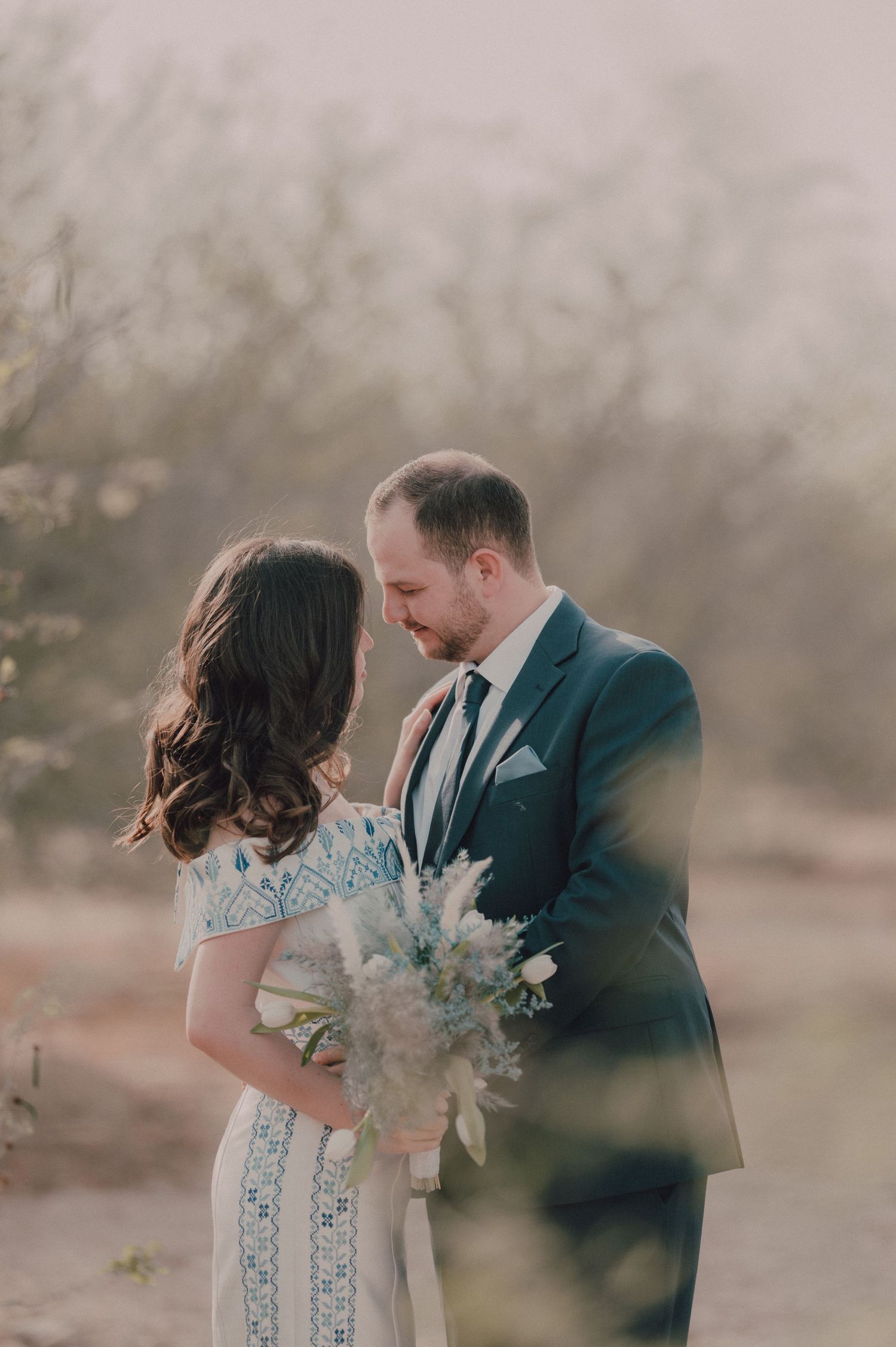 A couple shares an intimate moment during their outdoor wedding photoshoot in desert scenery.