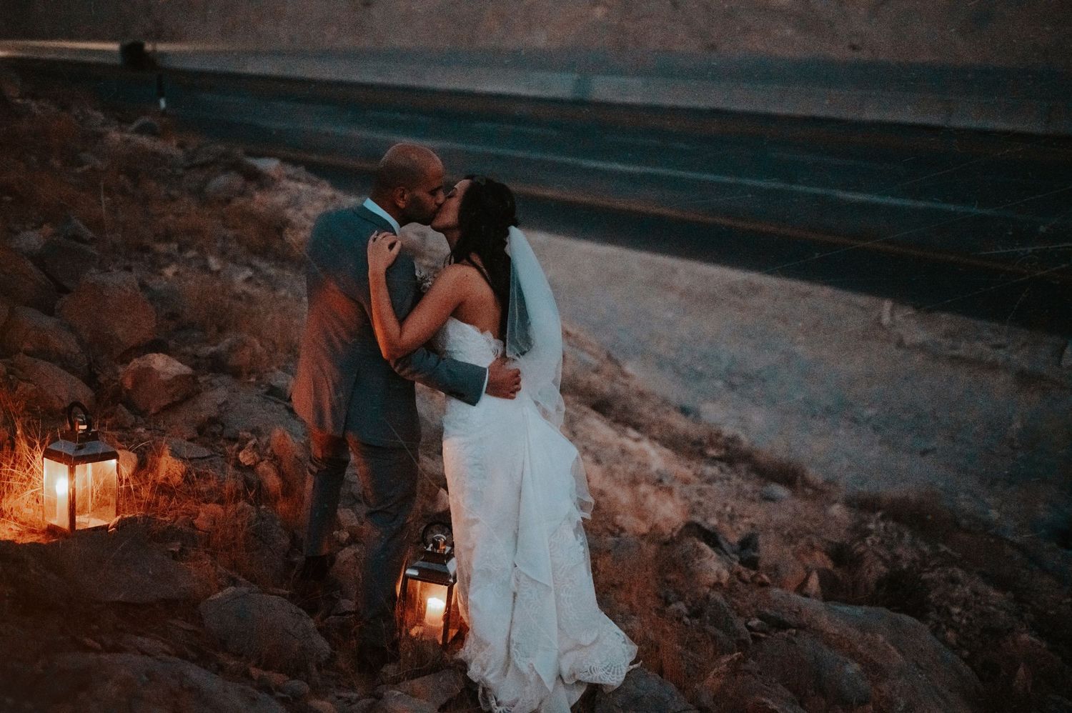 Couple sharing intimate moment by lantern light in desert setting.