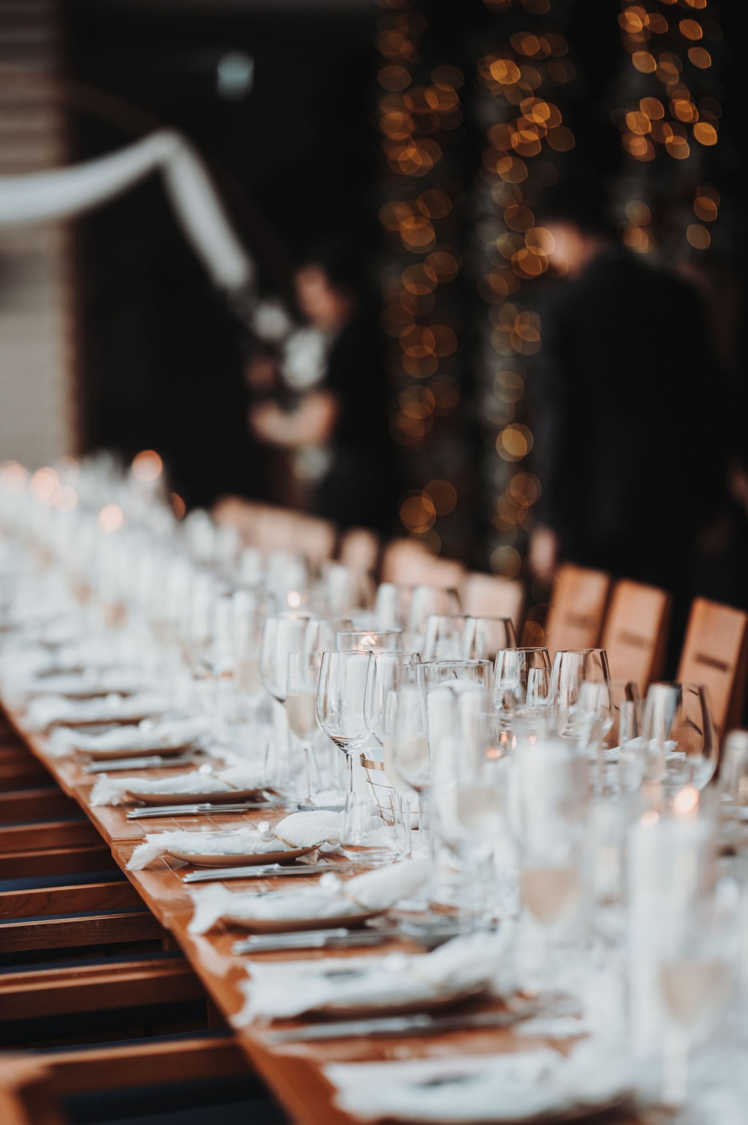 Long dining table set with elegant glassware and place settings for a formal event.