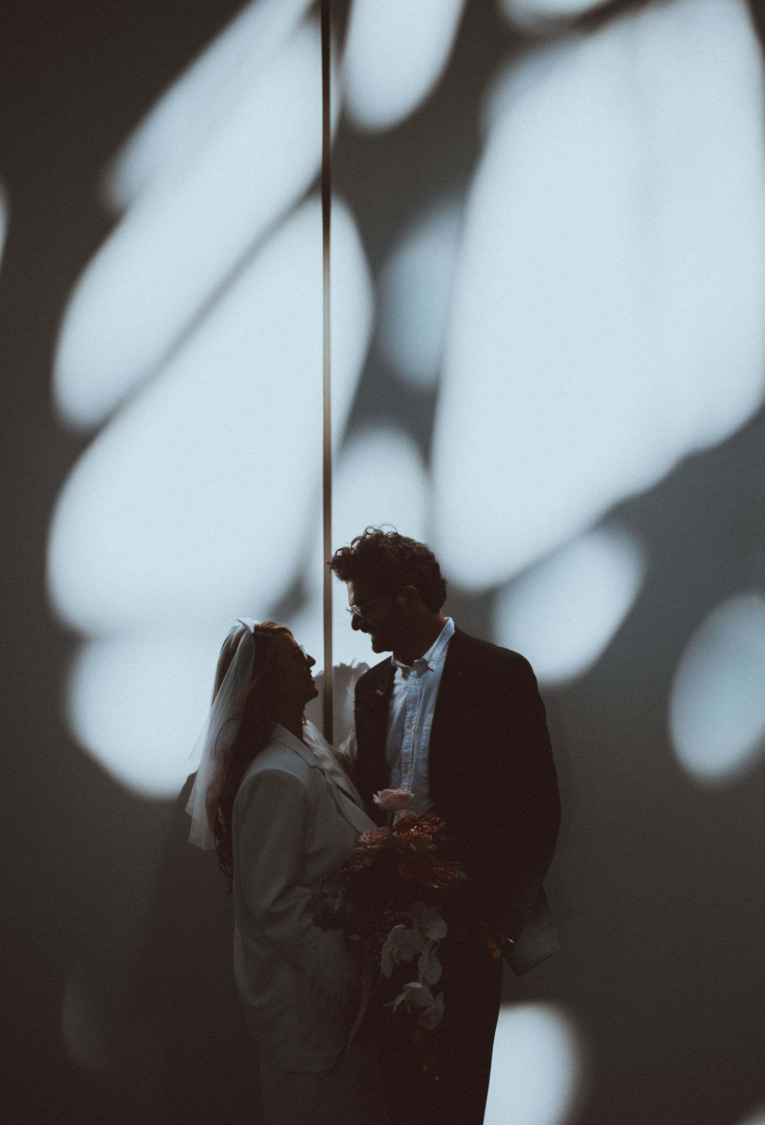 A romantic silhouette of a couple embracing against a wall with dramatic lighting.
