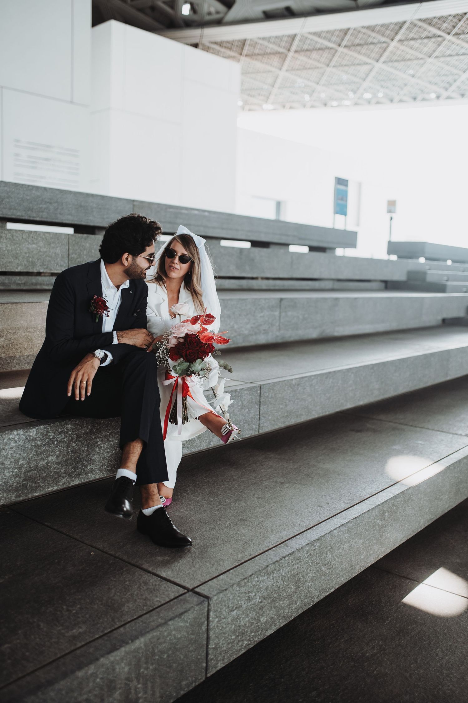 Wedding couple sharing tender moment on minimalist concrete steps.