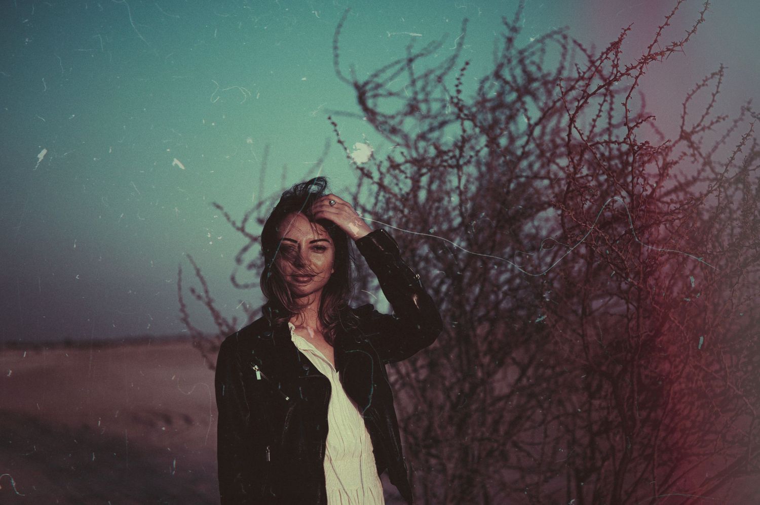 Artistic portrait with teal and burgundy tones in a natural setting.