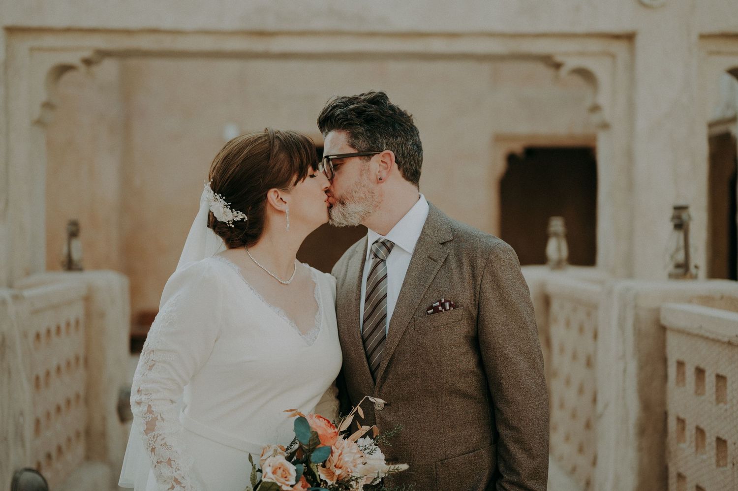 Wedding couple sharing tender moment against stone wall backdrop.