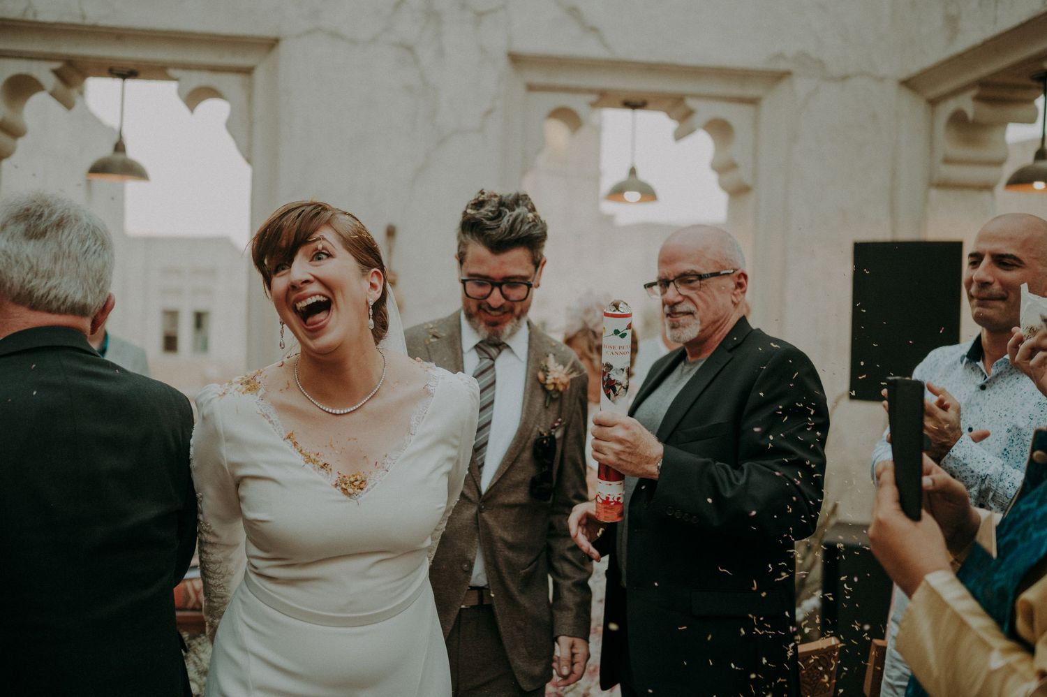 Guests celebrating at an elegant indoor wedding reception with confetti.