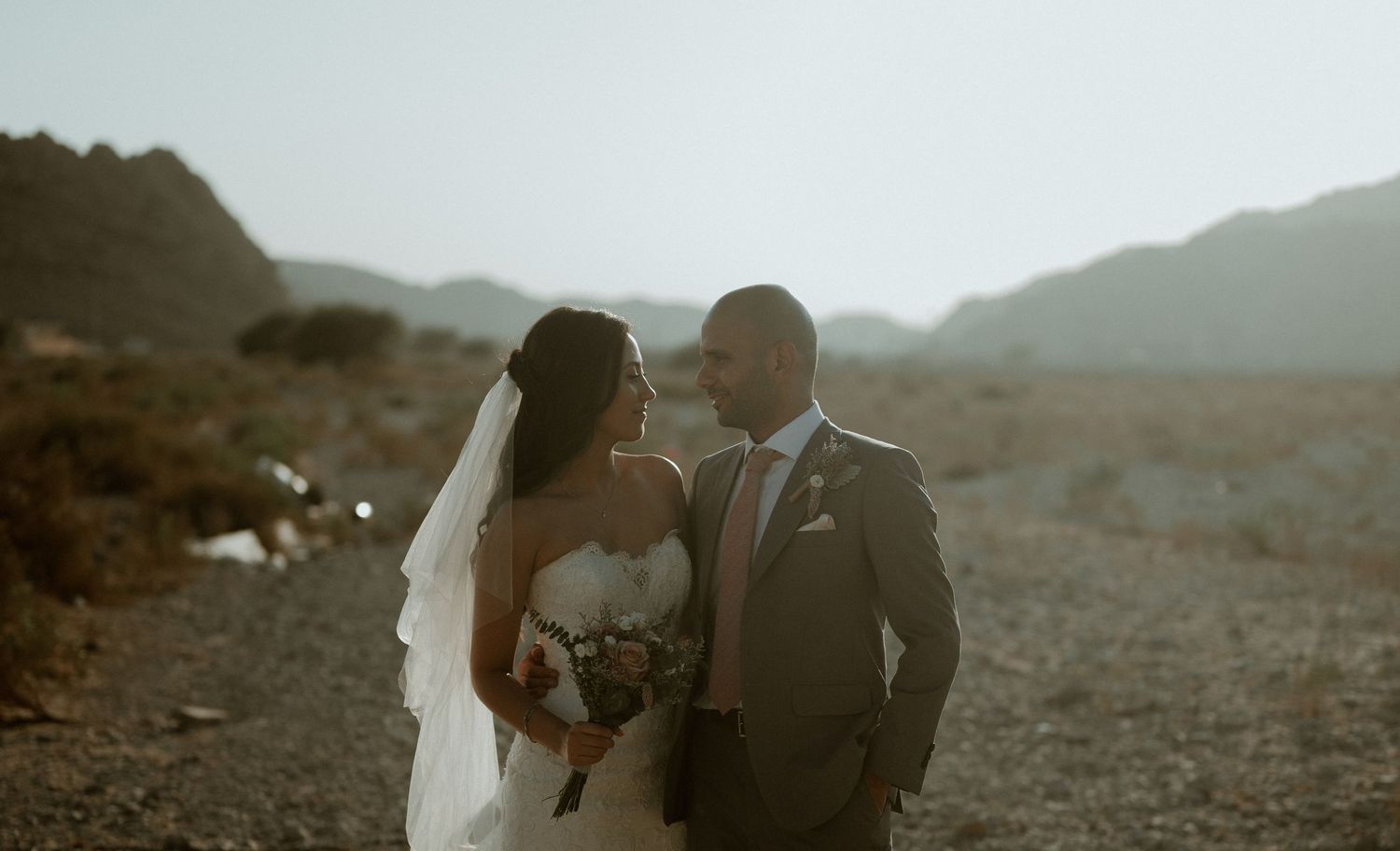 Romantic desert wedding scene with mountains in soft focus background.