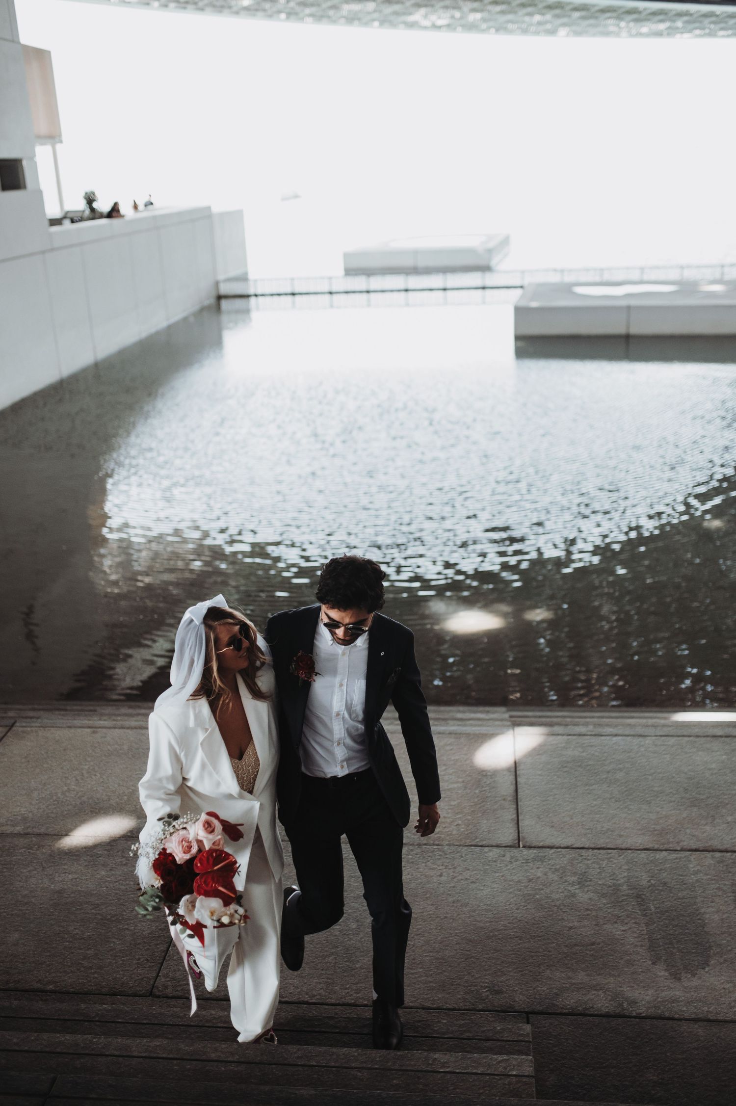 Wedding couple walking through modern architectural space with reflective floor.