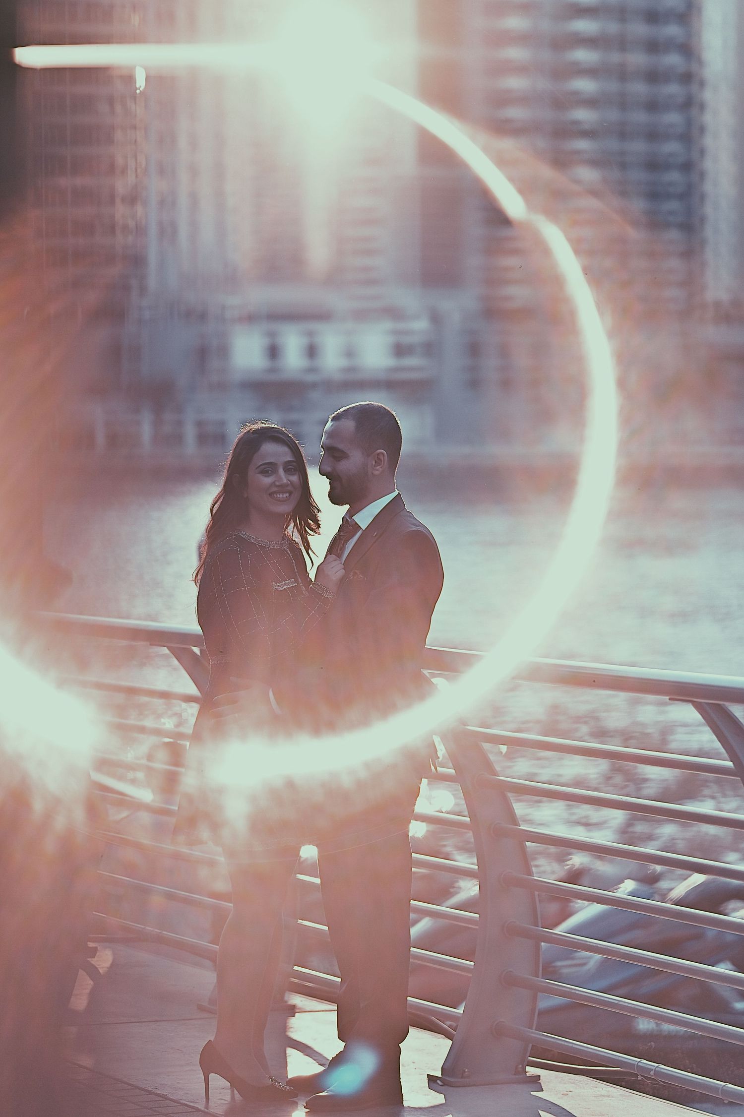 Artistic portrait of couple embracing with dreamy light effects and urban architecture.