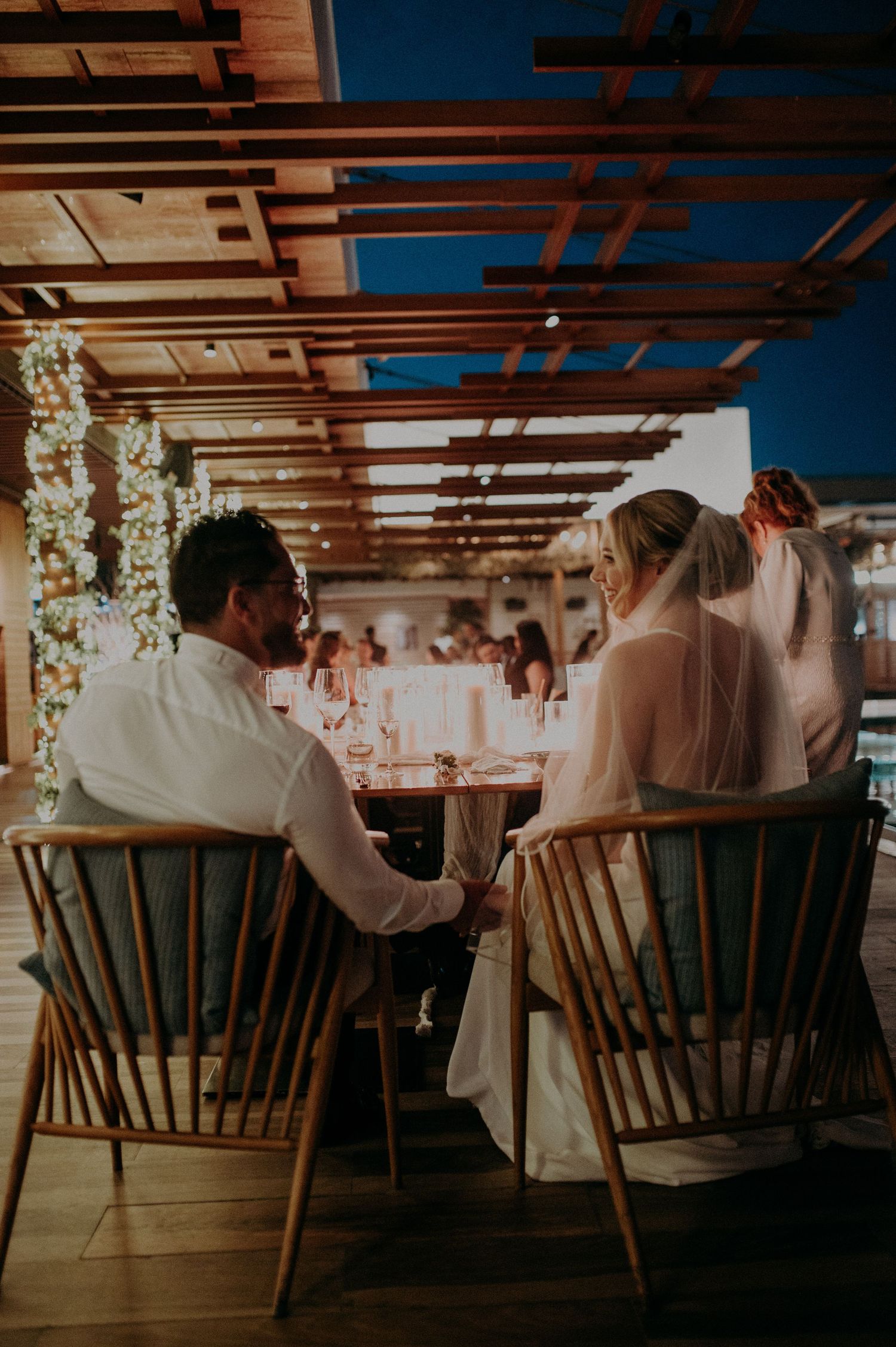 Row of wooden chairs with floral decorations at an indoor venue.