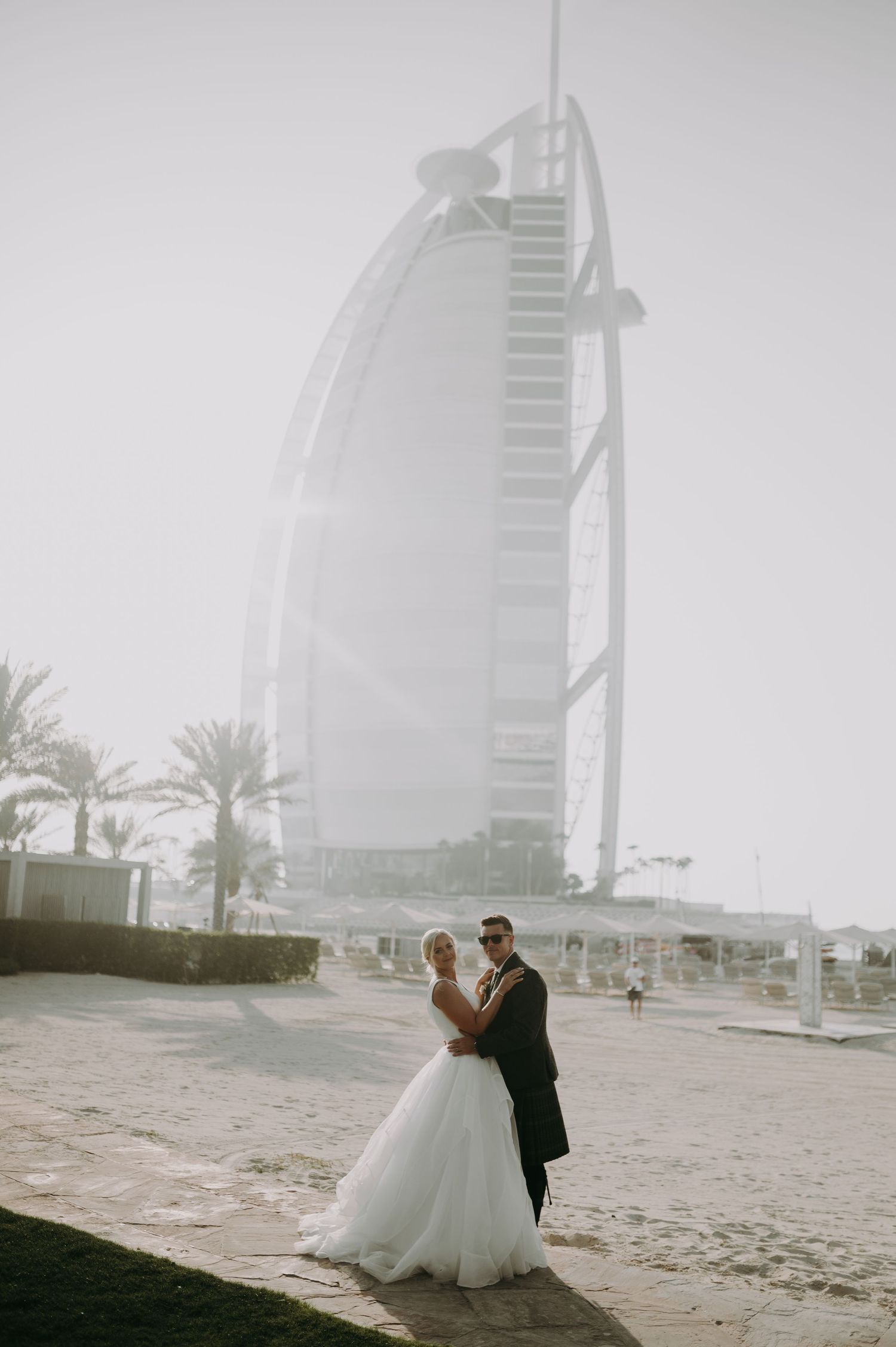 Couple sharing a romantic moment on Dubai beach with the Burj Al Arab in the background.
