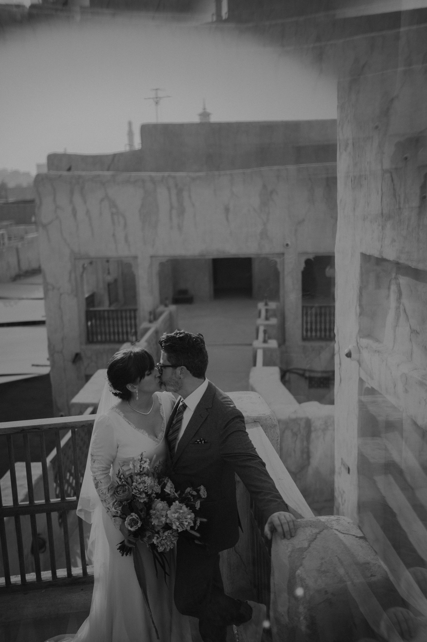 Wedding photography in black and white showing couple against architectural backdrop.