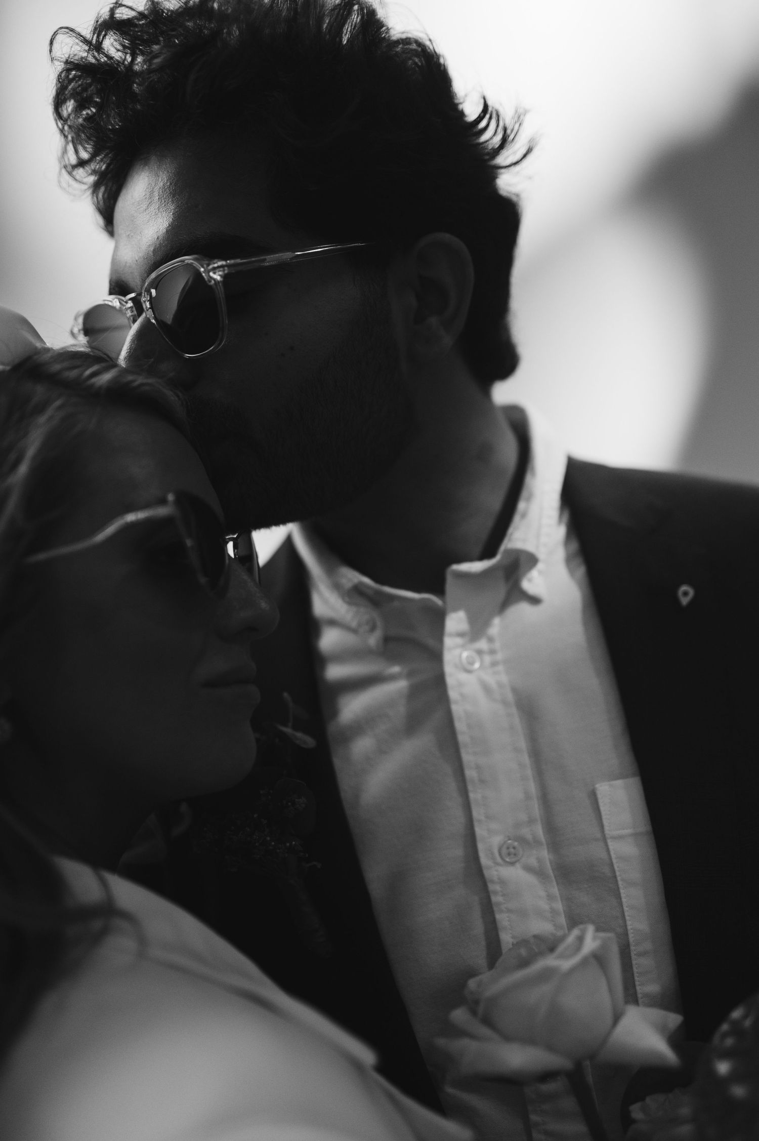 A black and white close-up portrait of someone wearing sunglasses and a white shirt.