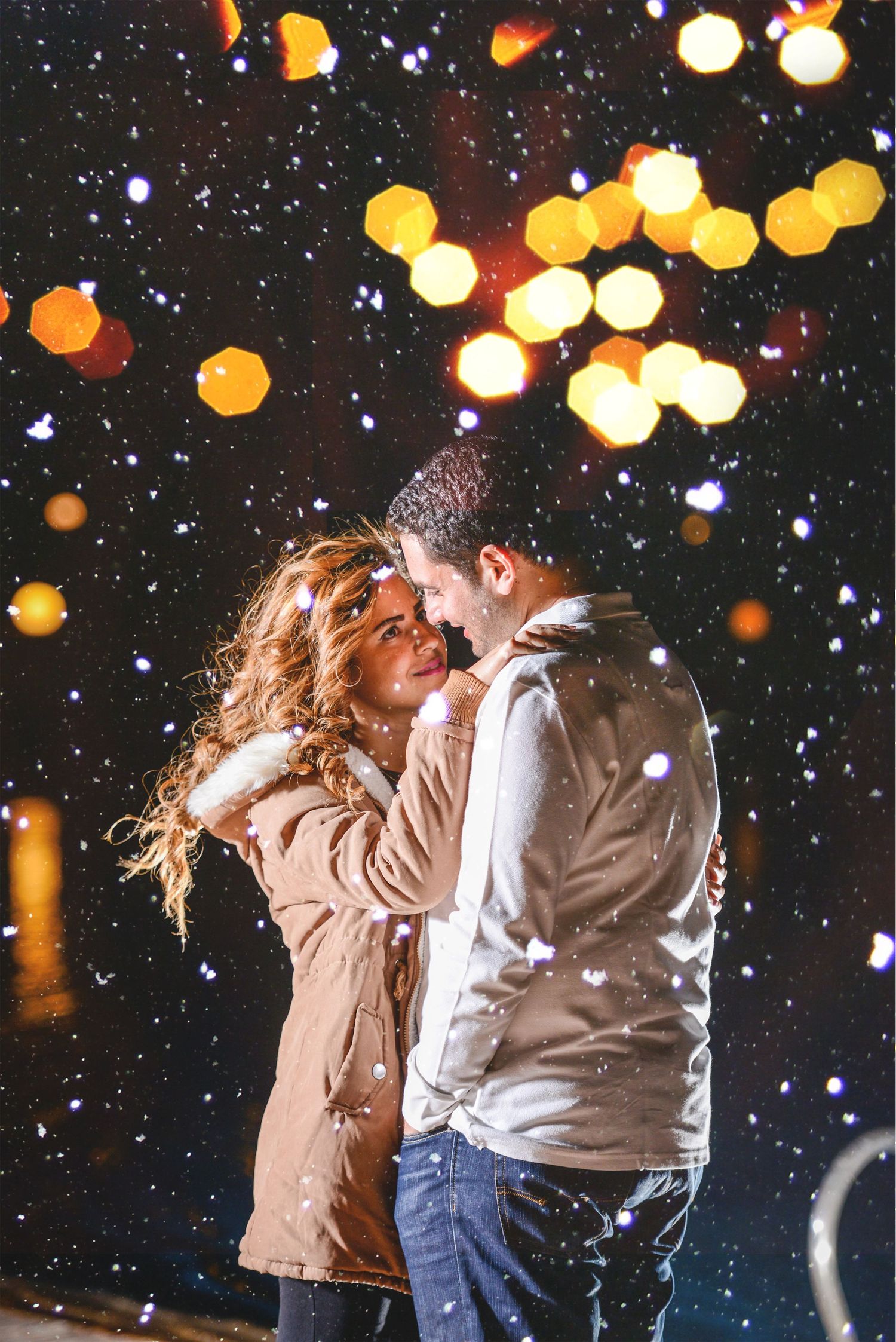 Romantic winter scene with falling snow and glowing bokeh lights at night.