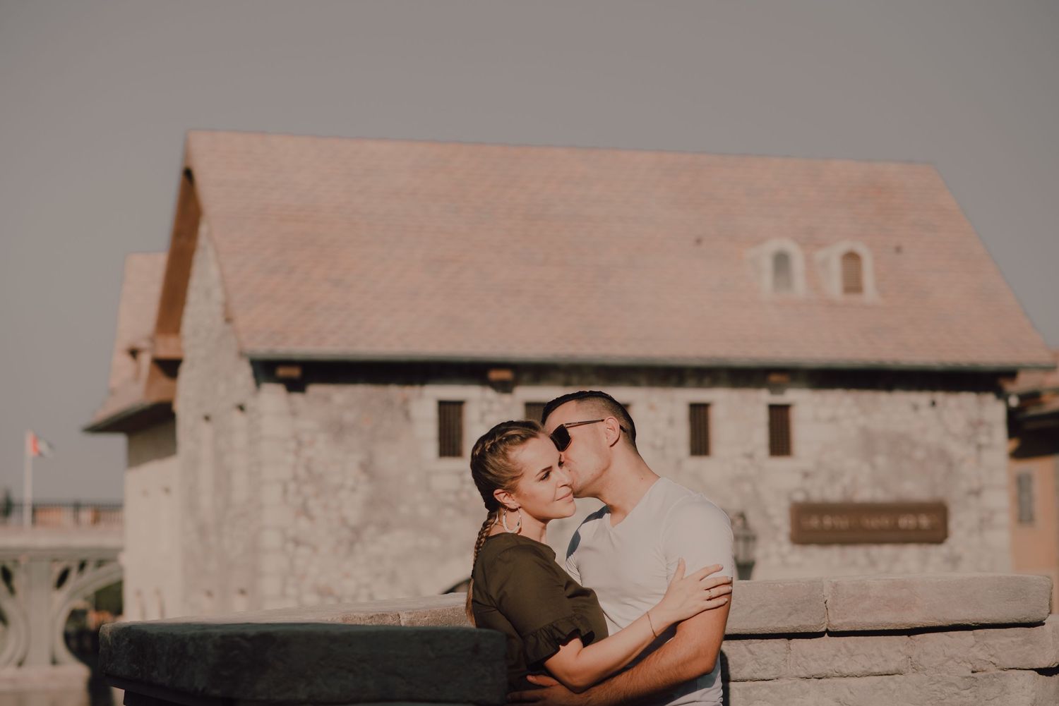 A romantic couple embraces during a sunset photoshoot against rustic architectural backdrops.