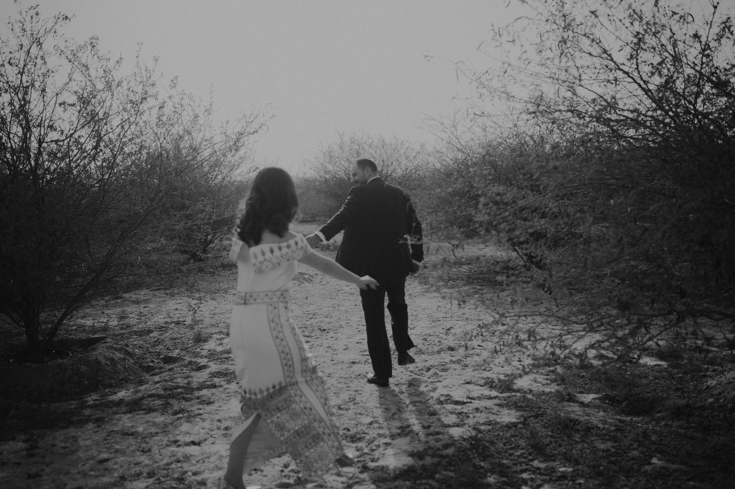Artistic black and white shot of a couple strolling through desert terrain.