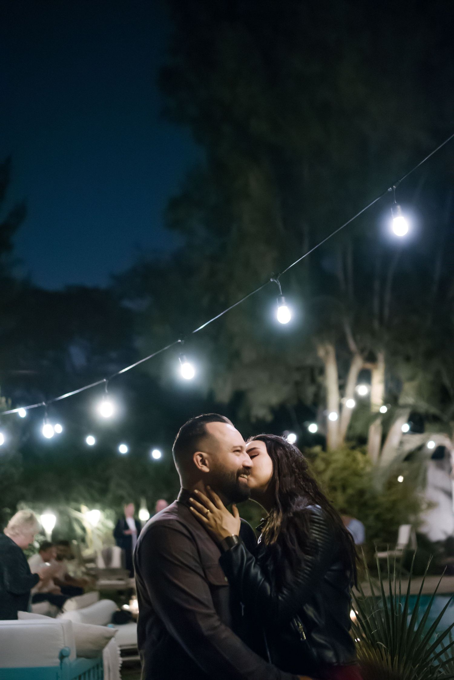 Romantic evening scene with string lights illuminating a couple's intimate moment.