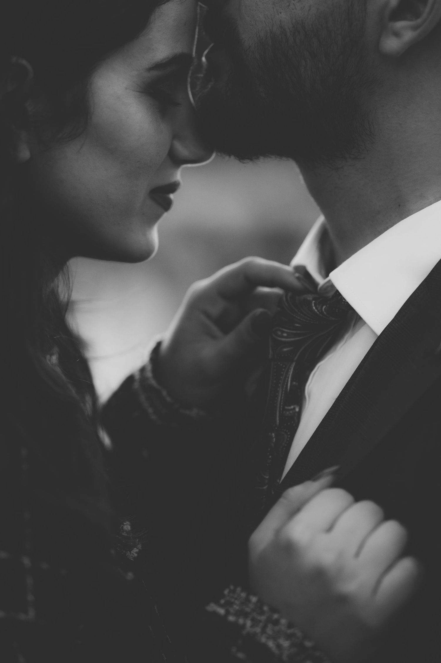 Black and white close-up of couple in formal wear sharing tender moment.