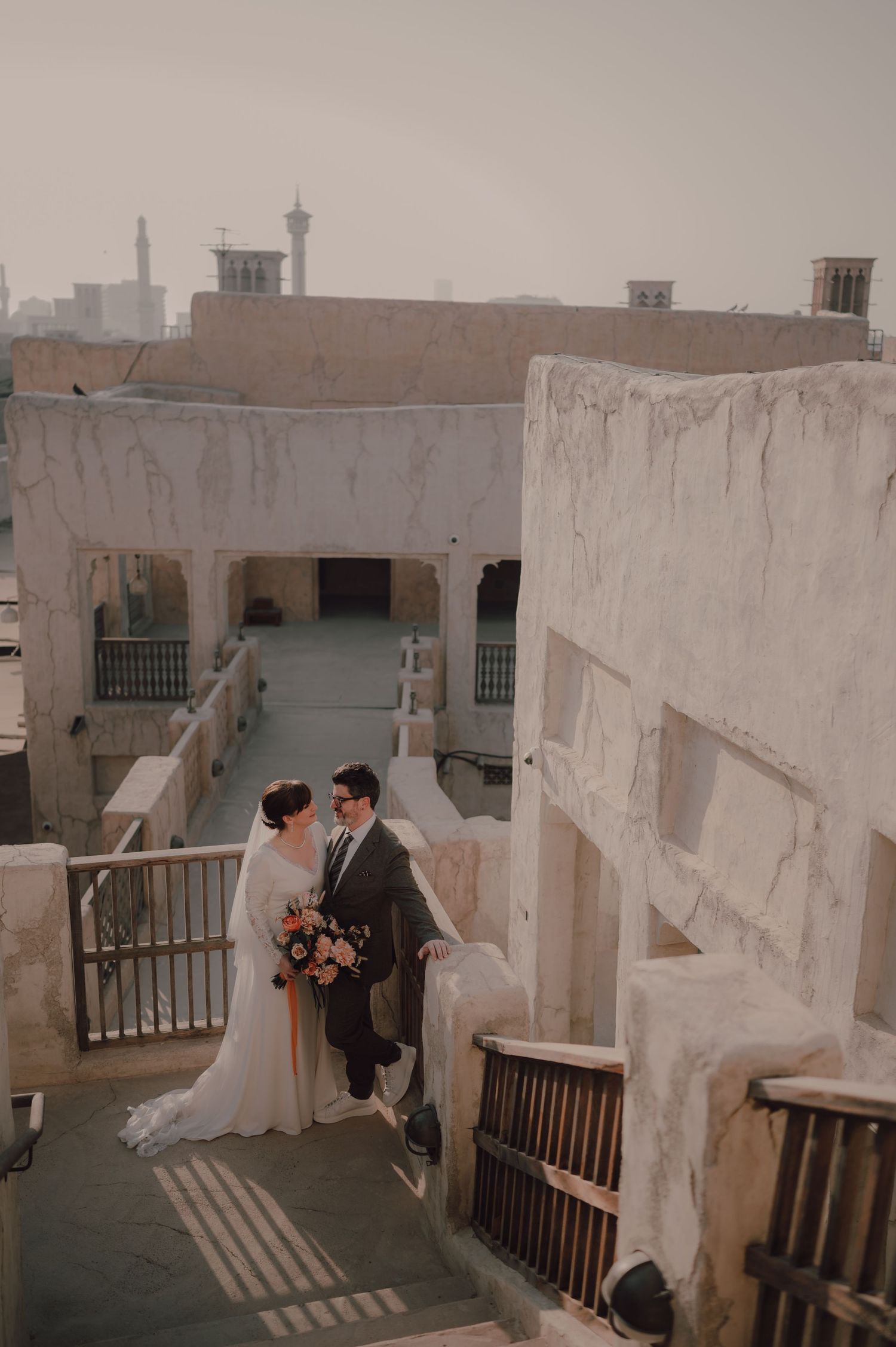 Wedding couple photographed on rooftop terrace with white stone walls and traditional architecture.