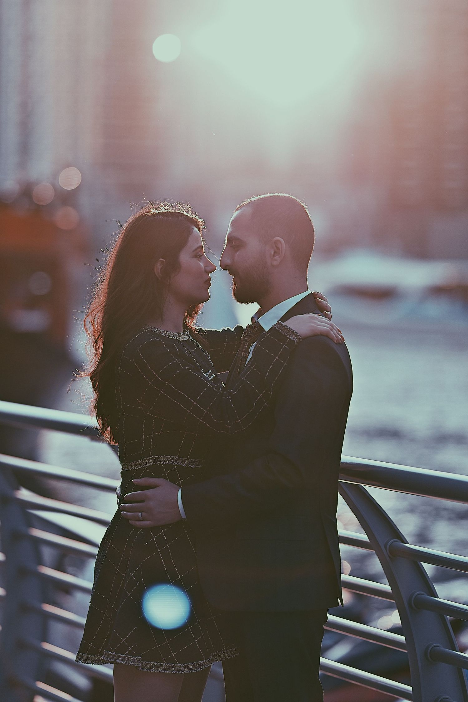 Couple sharing a romantic moment against blurred cityscape during golden hour.
