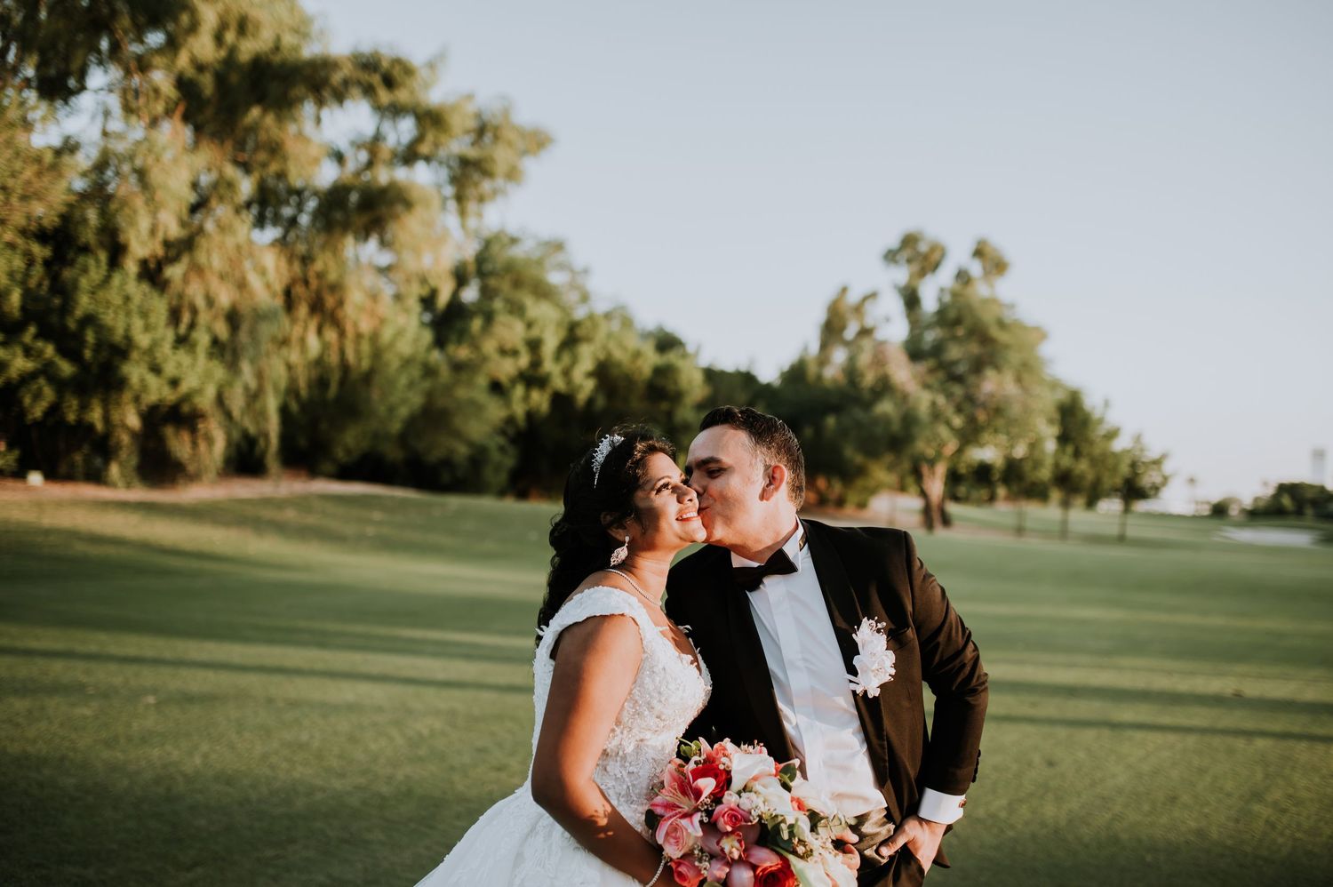 A romantic outdoor photo session on a manicured lawn with trees in the background.