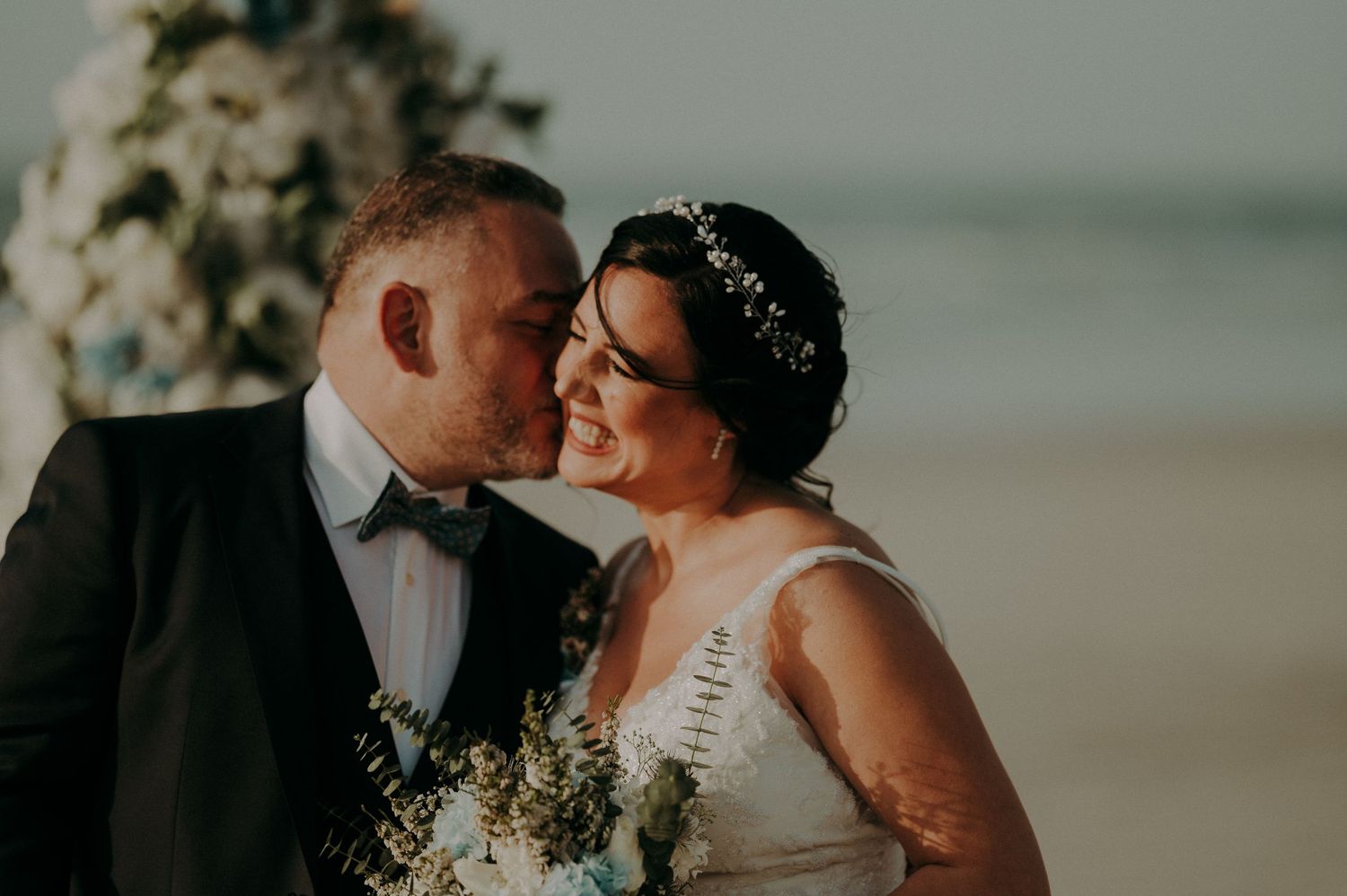 A romantic beach wedding moment captured during golden hour with soft lighting.