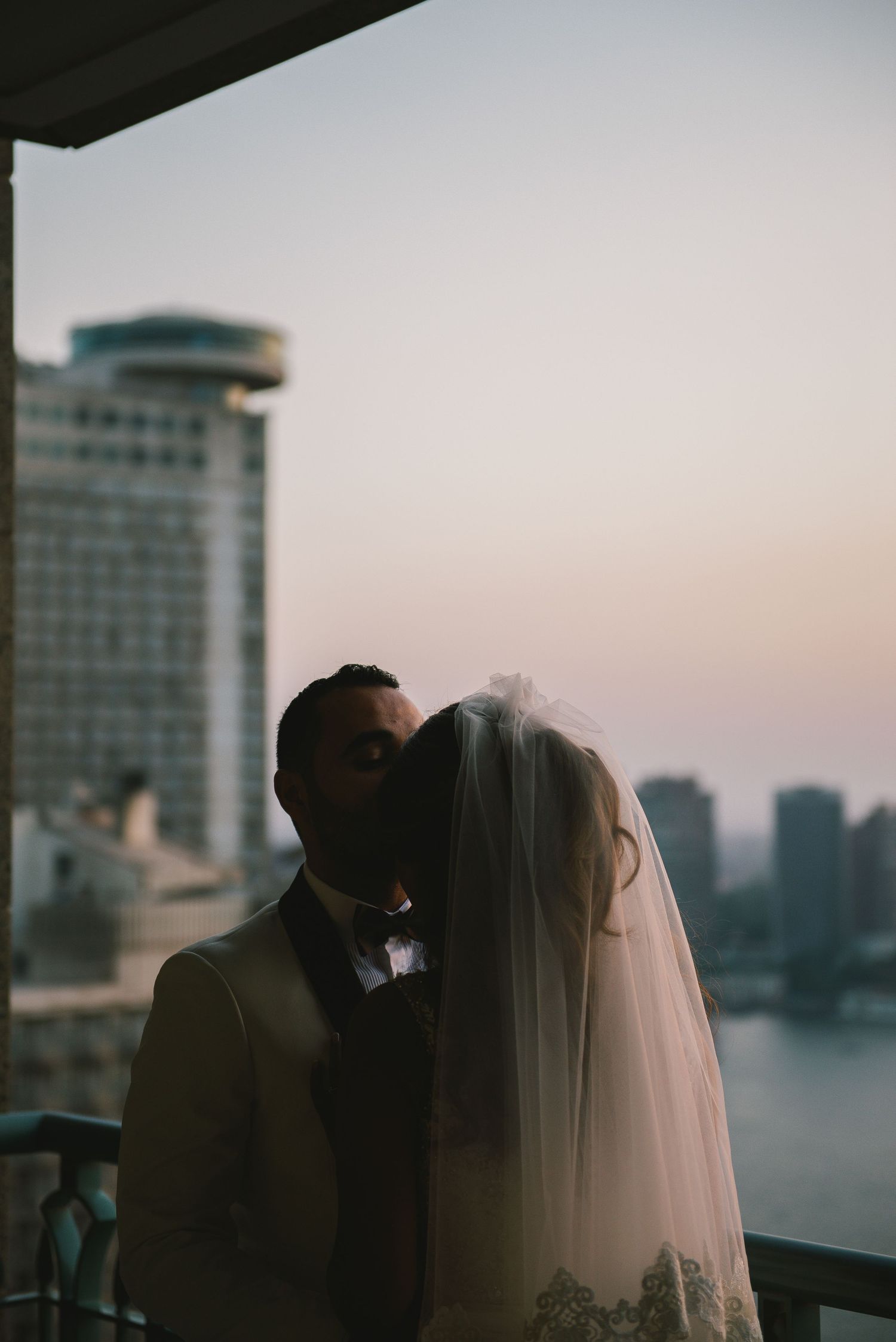 Romantic silhouette of couple against sunset waterfront view with city skyline.